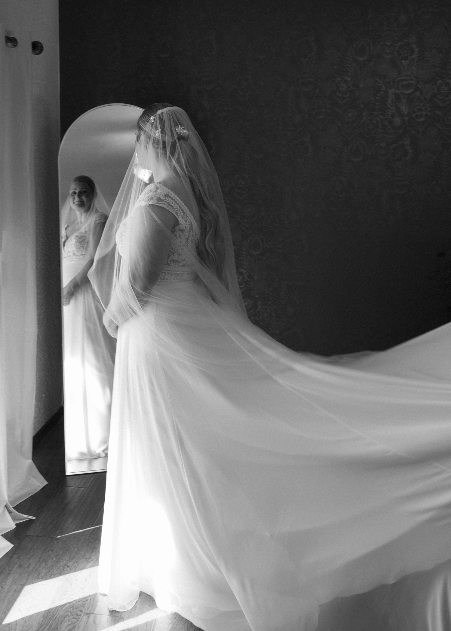 Dramatic flowing wedding dress veil captured in motion against dark background.