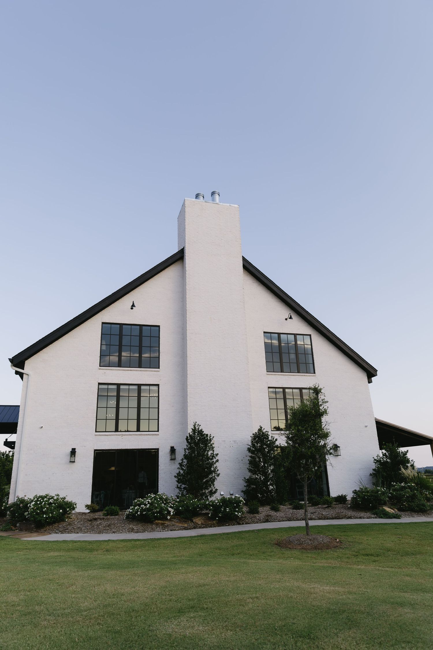 Modern white church building with angular architecture and large windows captured from multiple angles on a grassy lawn.