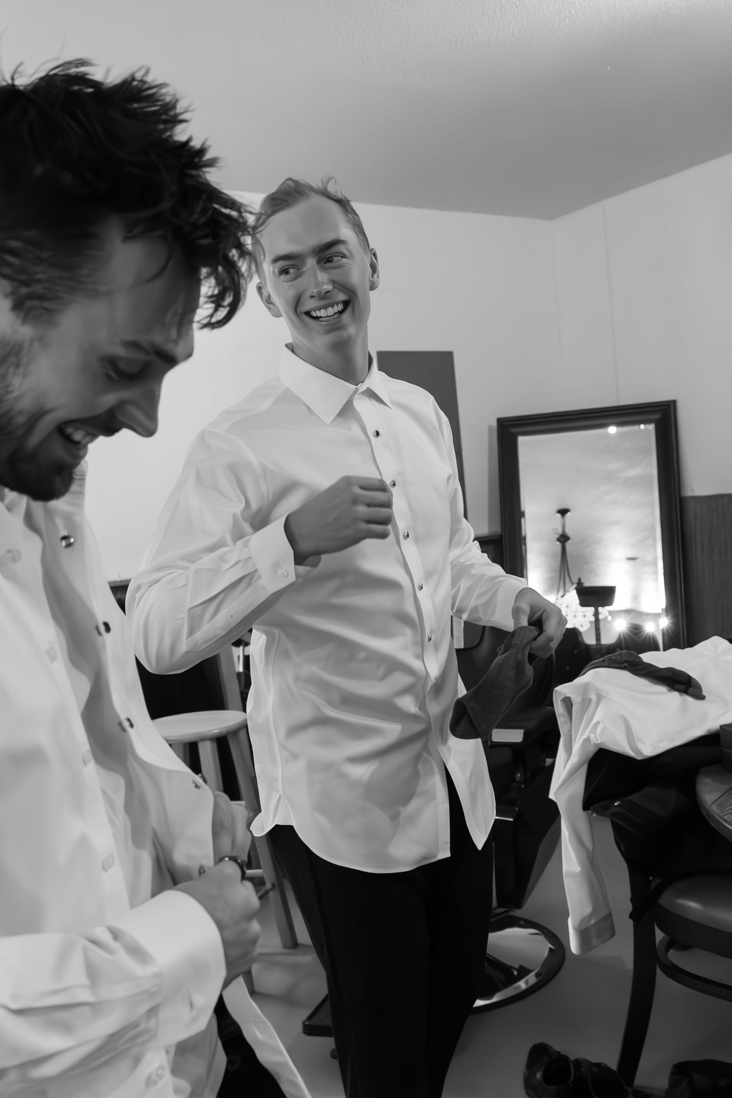 A series of black and white candid photos show people in white shirts laughing together indoors.