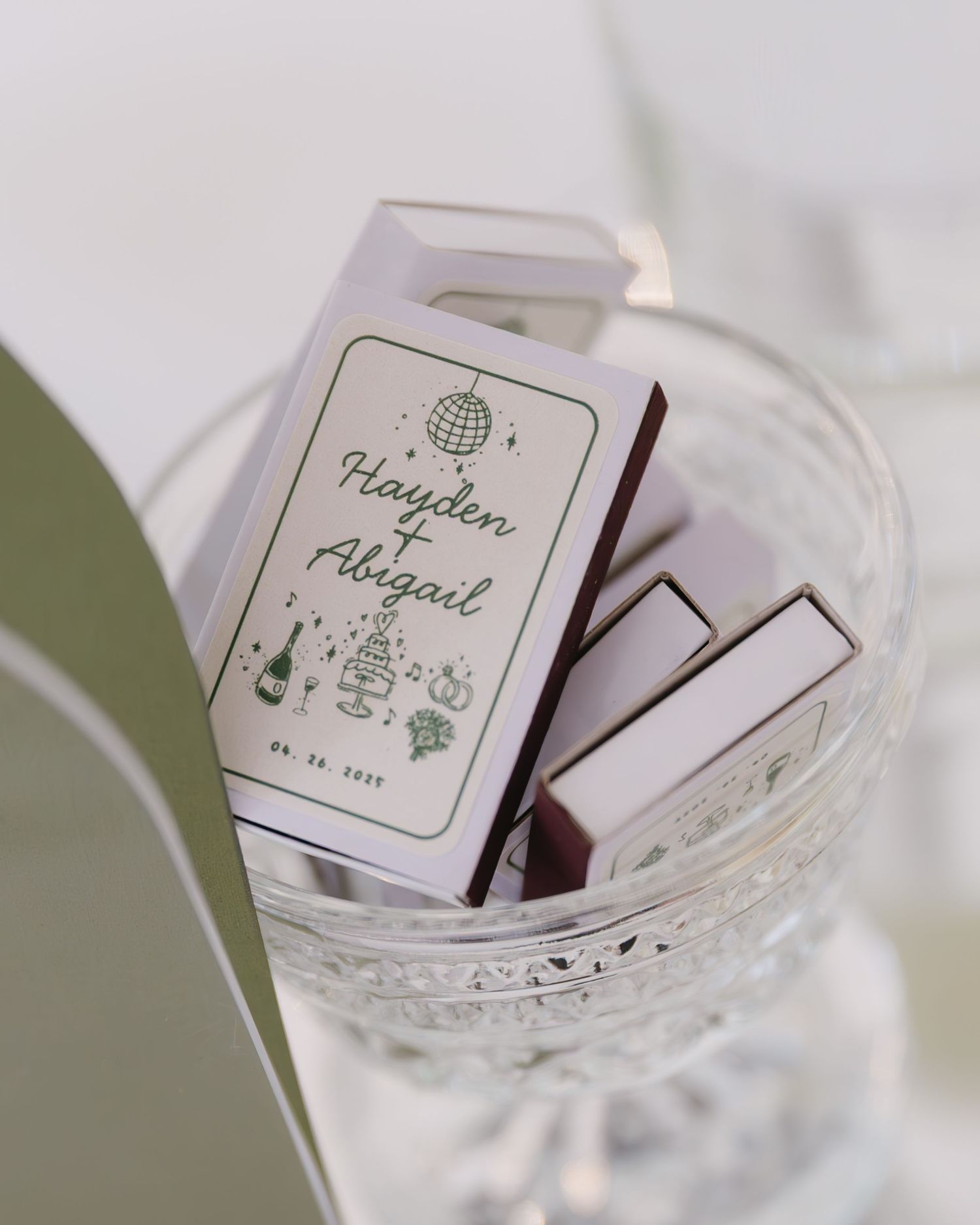 Custom wedding matchboxes with couple's names displayed in a crystal glass container.