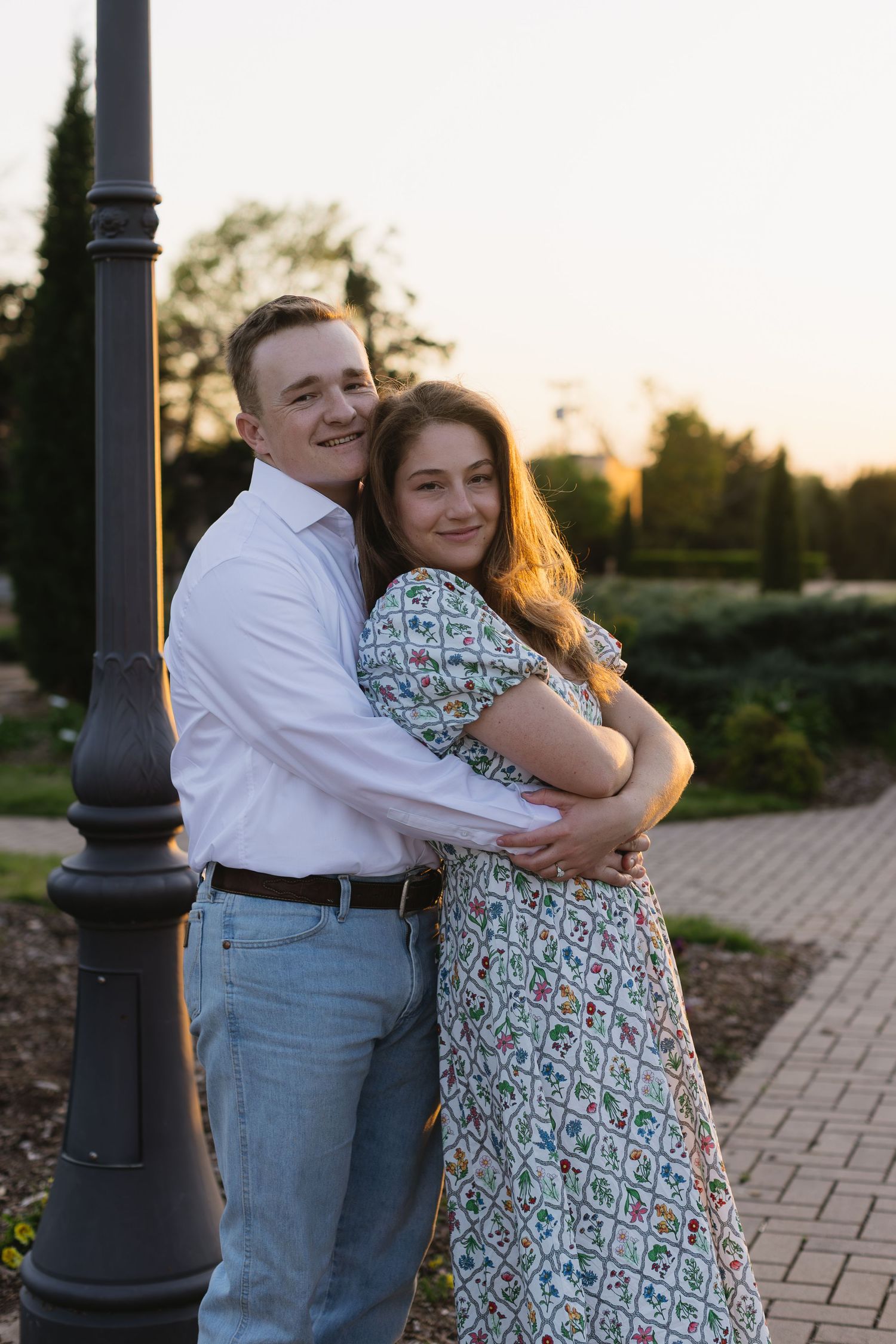 Golden hour portrait session with couple embracing near decorative lamp posts.
