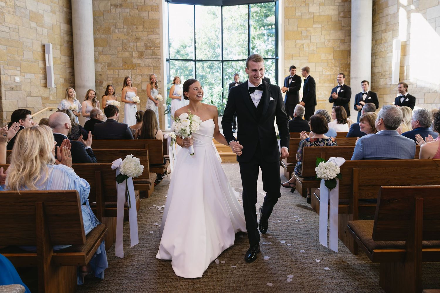 A wedding ceremony exit in a chapel with brick walls and wooden pews.