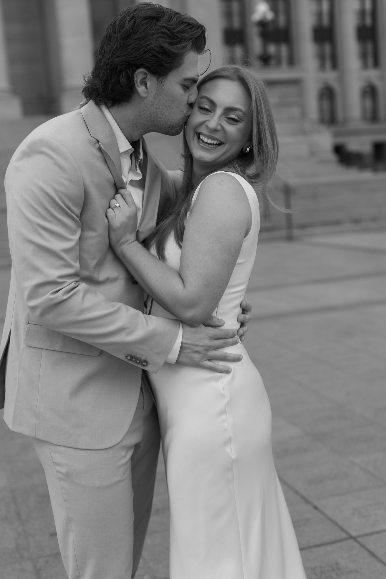 Black and white photo of a couple sharing an intimate moment in formal attire.