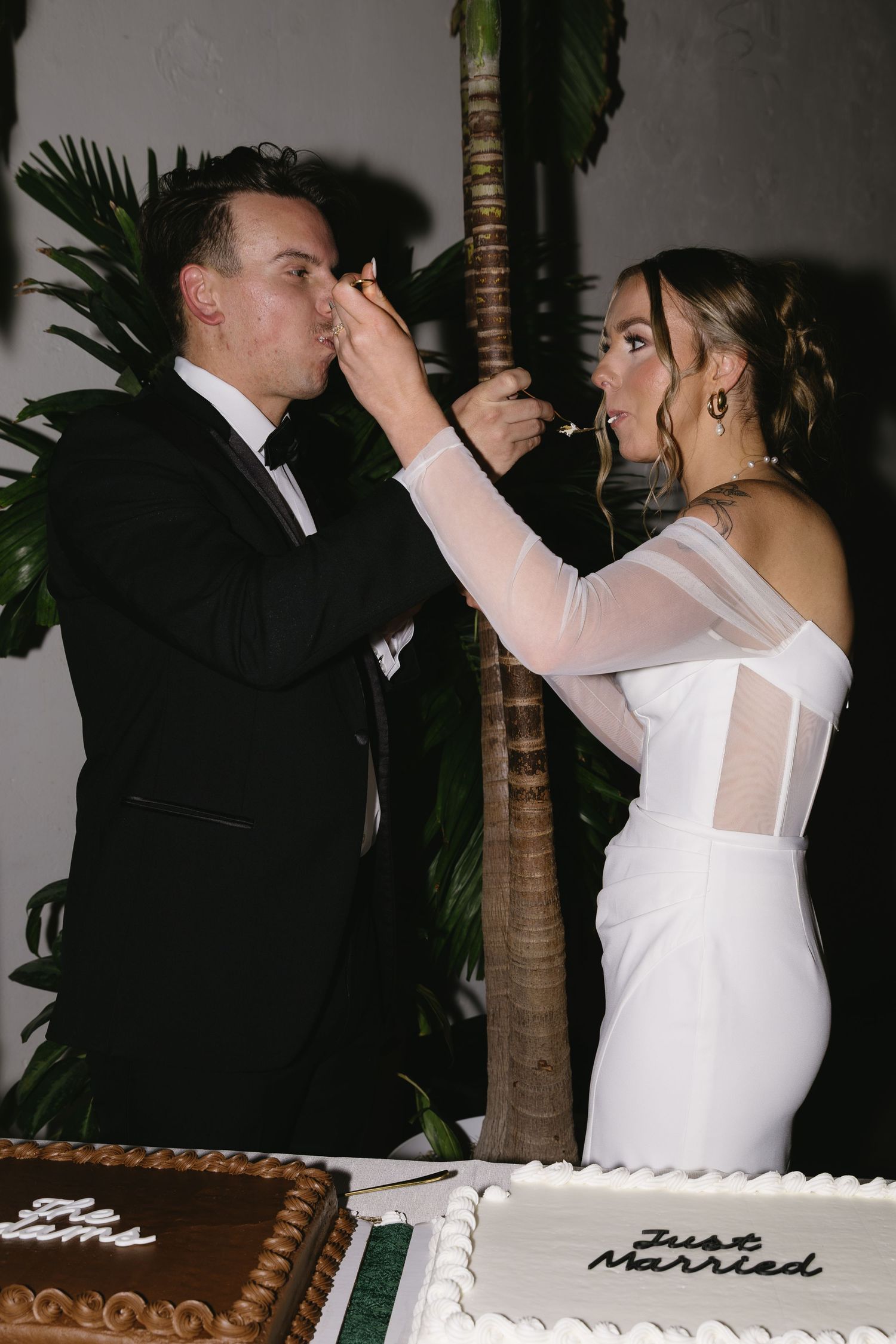 Wedding couple sharing a celebratory moment next to their white wedding cake.