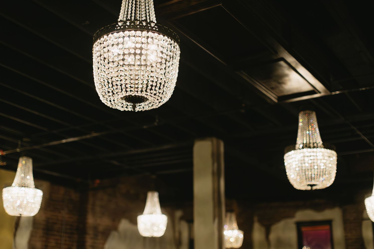 Crystal chandeliers hanging from dark ceiling creating elegant ambient lighting.
