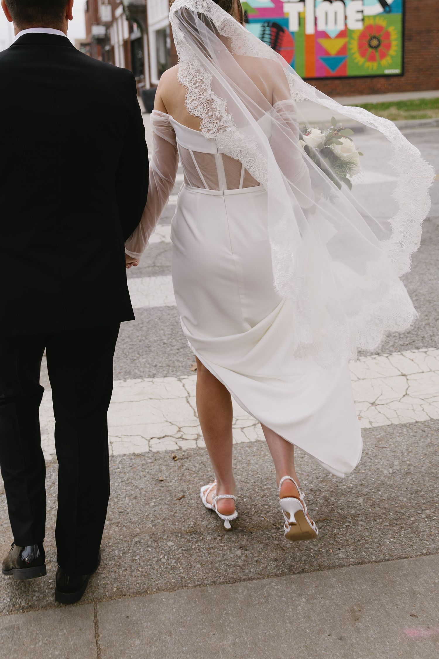 Back view of couple walking showing bride's flowing dress and veil.