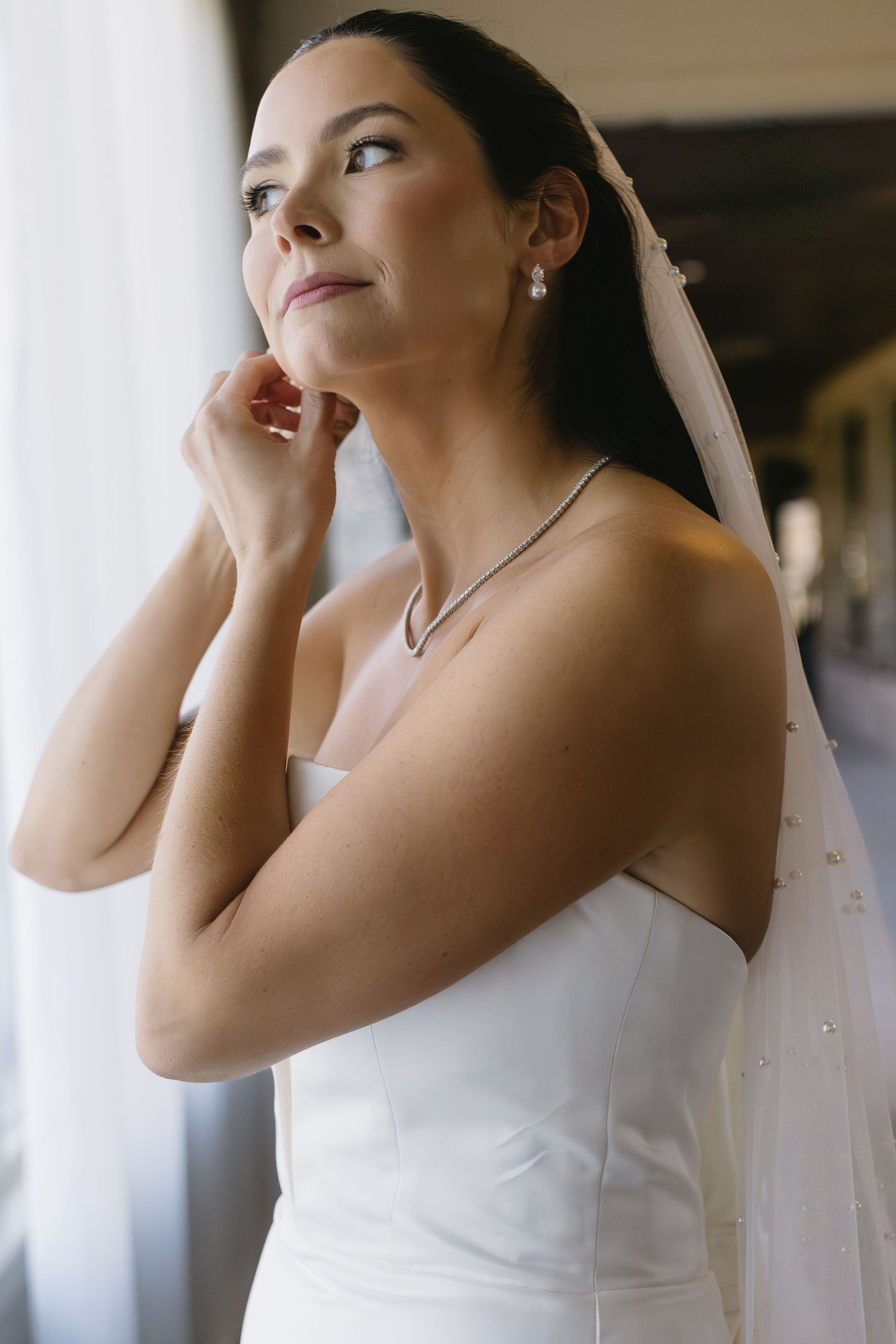 Close-up details of a white wedding dress and veil in natural light.