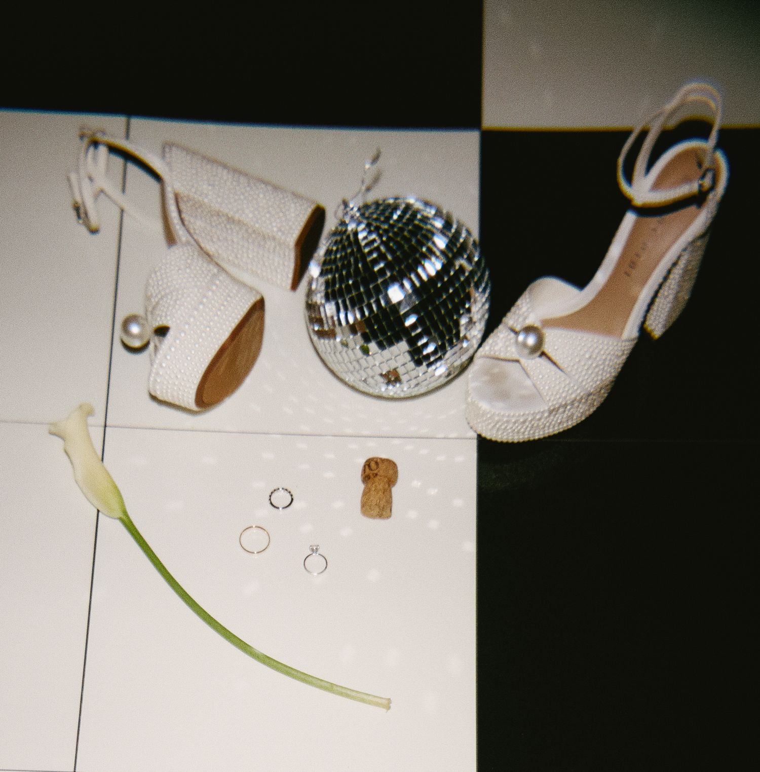 Wedding accessories including sparkly heels and disco ball on white surface.