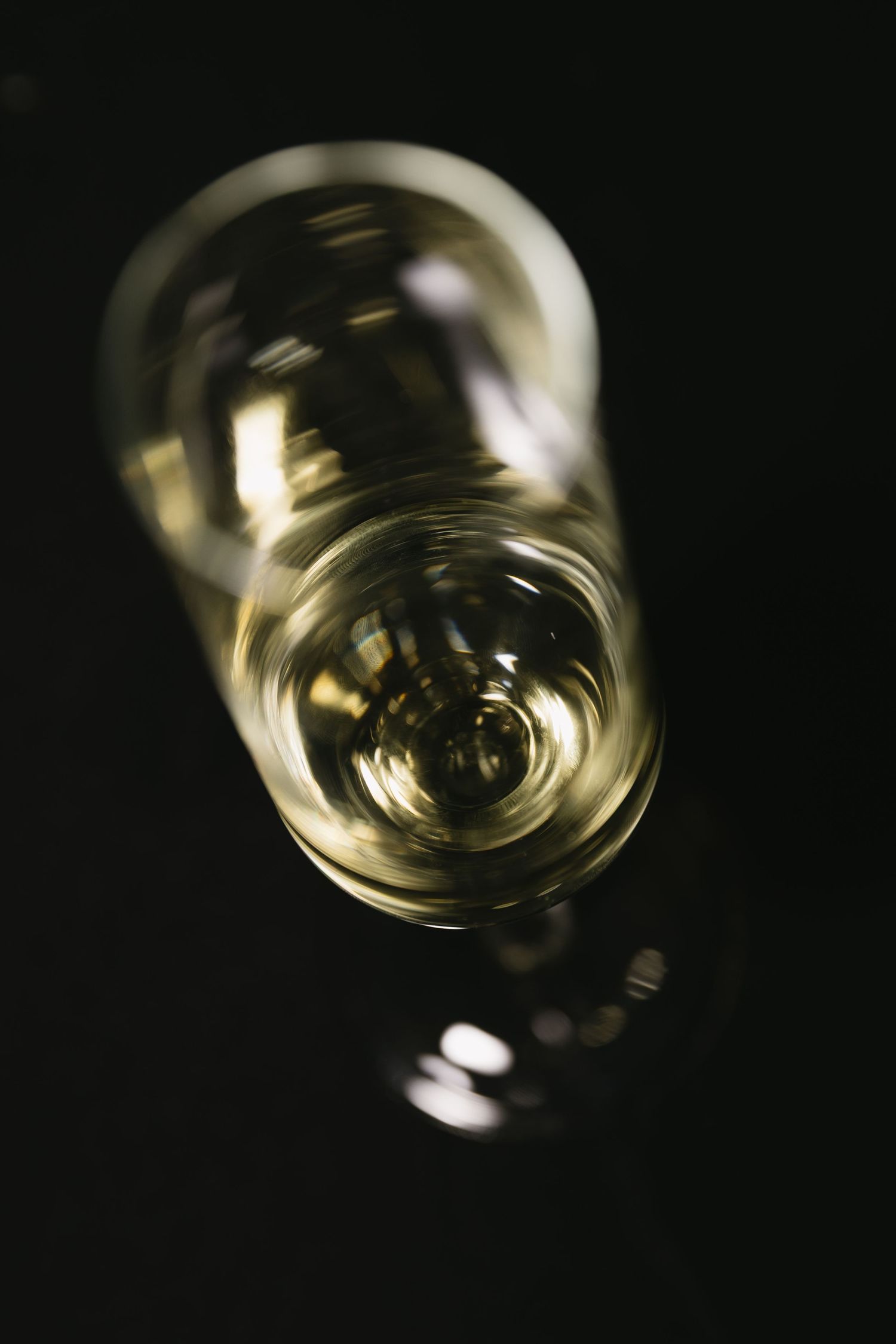 Abstract close-up shot of a champagne glass with golden liquid creating circular reflections.