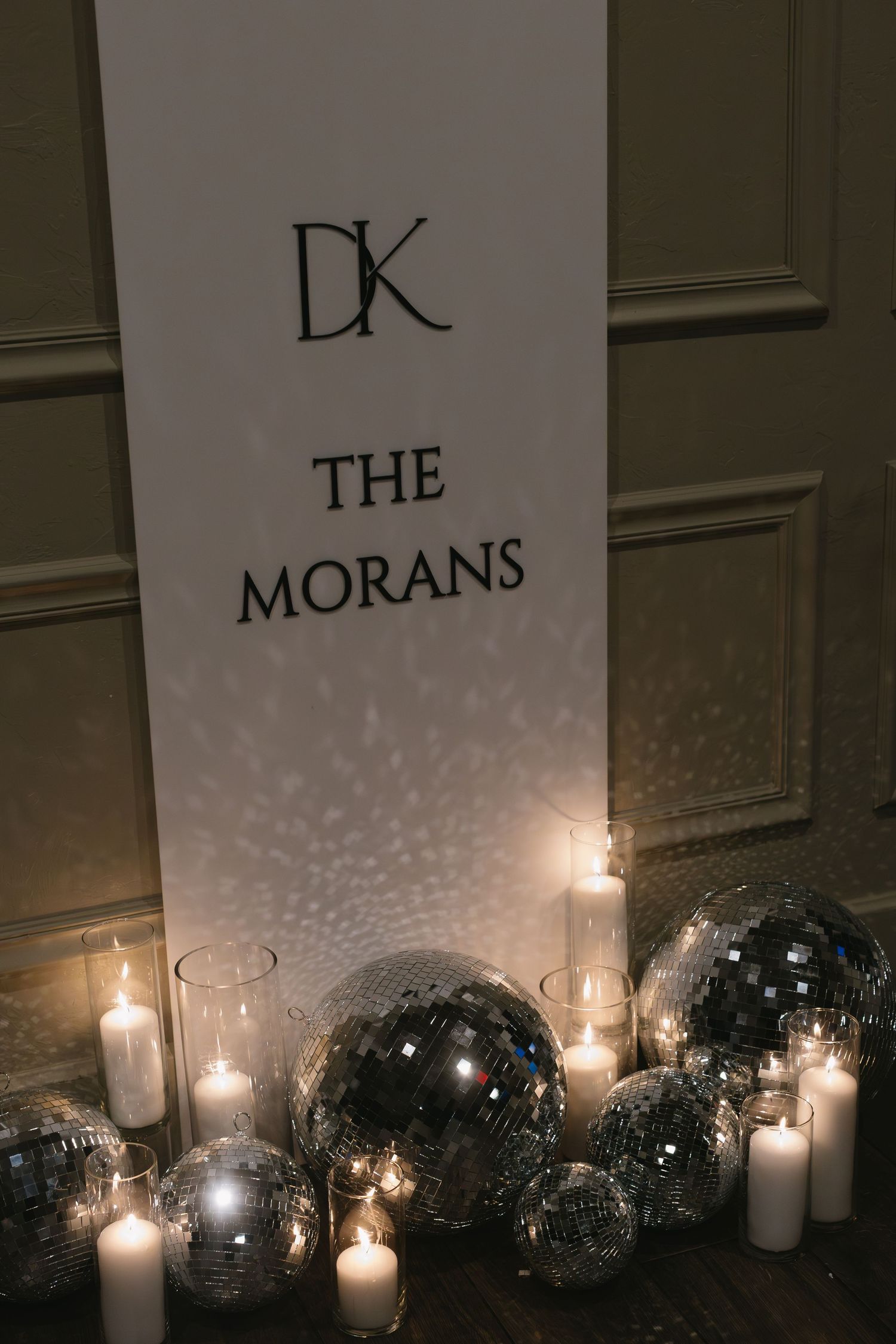 Disco balls and candles create a romantic ambiance against a wall with text signage.