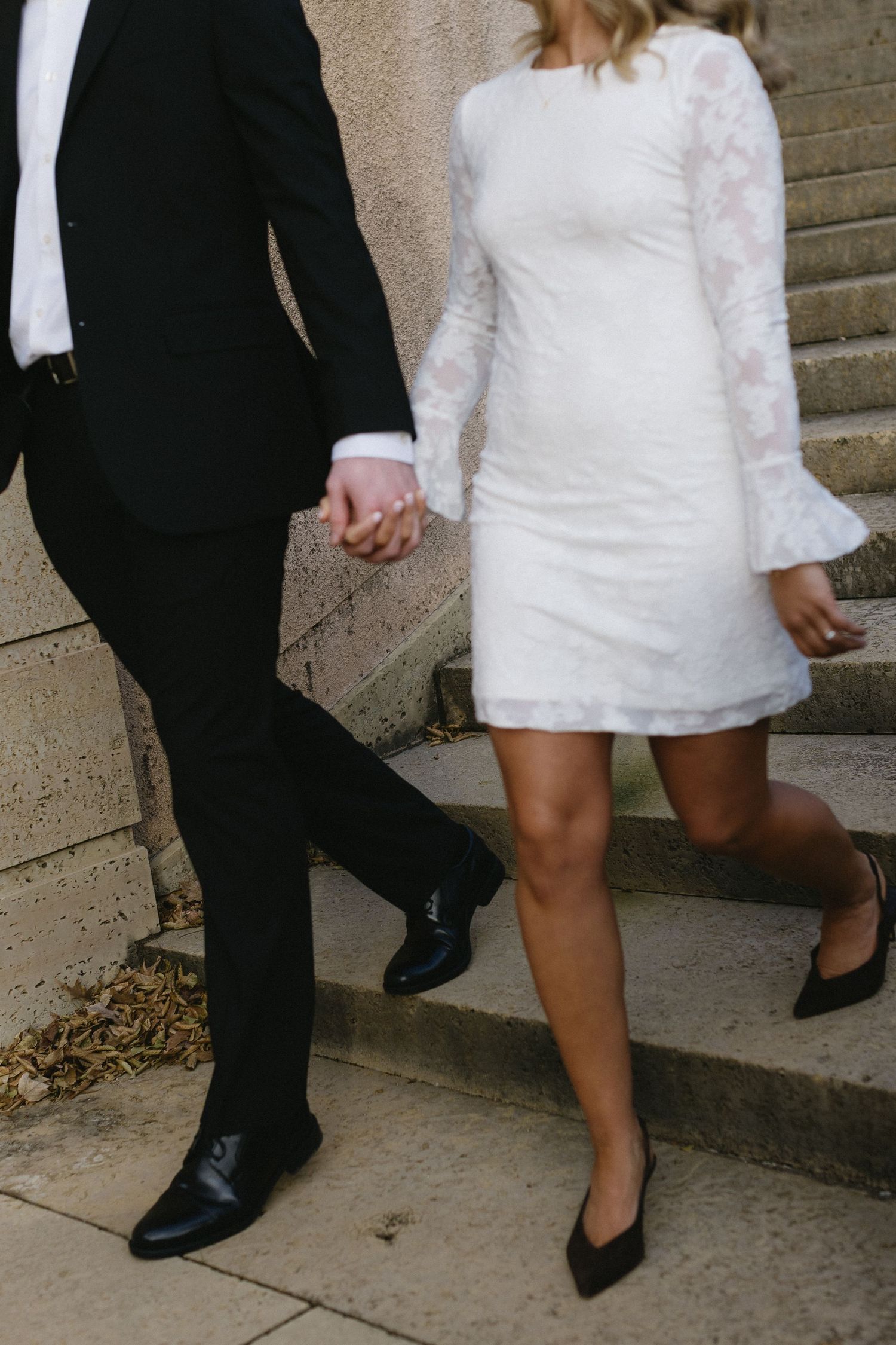 Close up of formal shoes and dress hem as couple walks down stone steps.