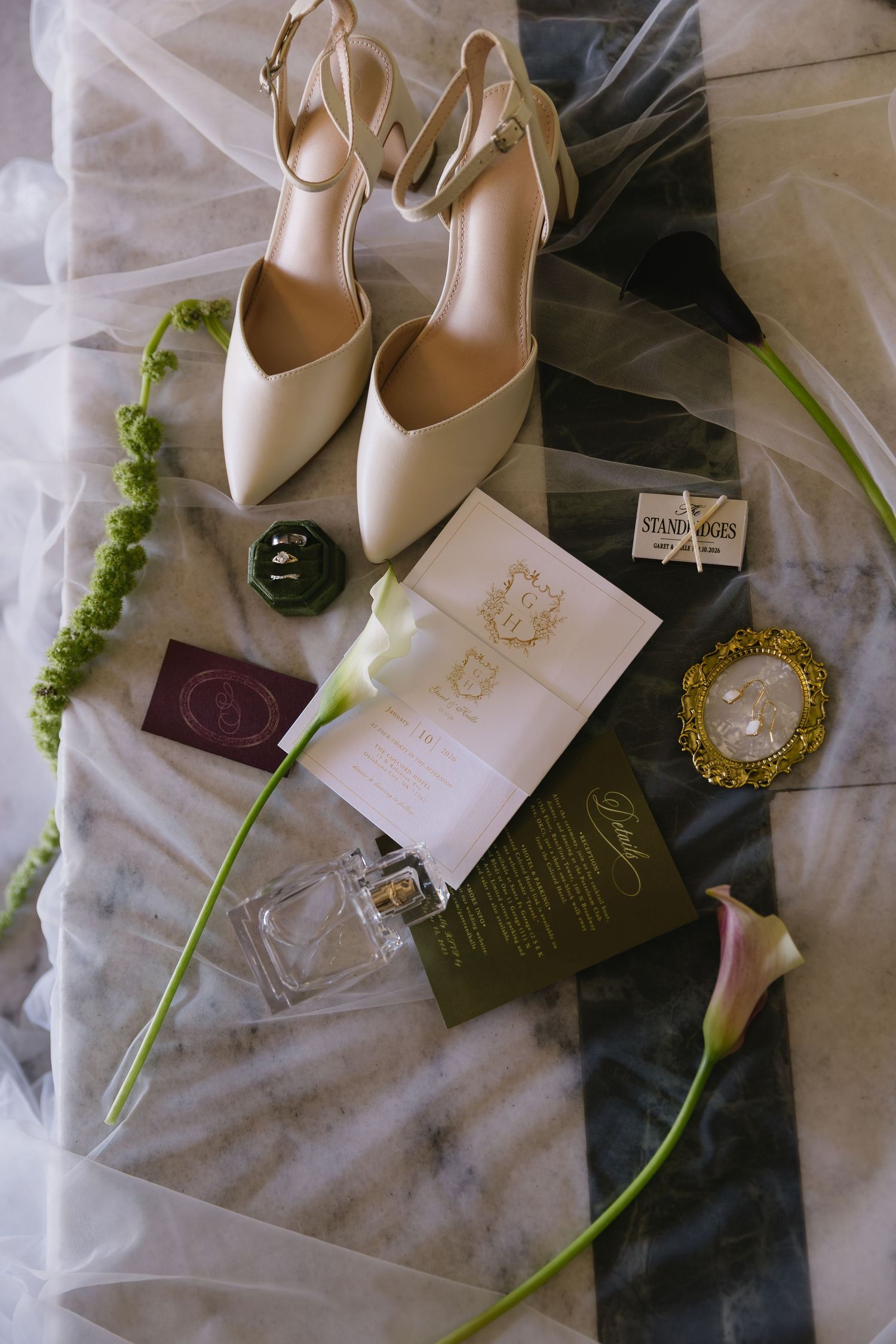 Elegant bridal shoes and accessories displayed with white flowers on delicate fabric.