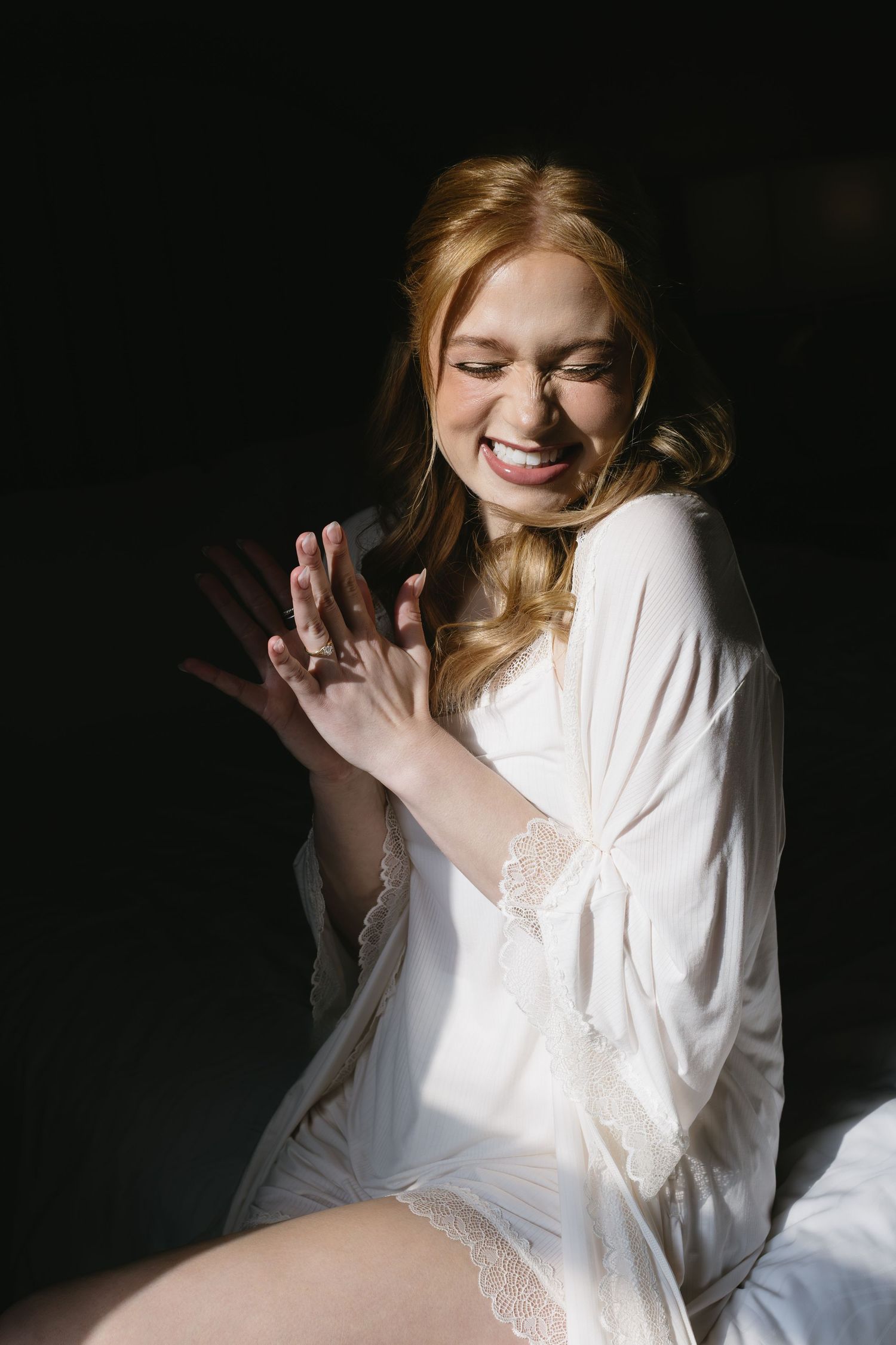 Person in white lace robe sitting in dramatic lighting.