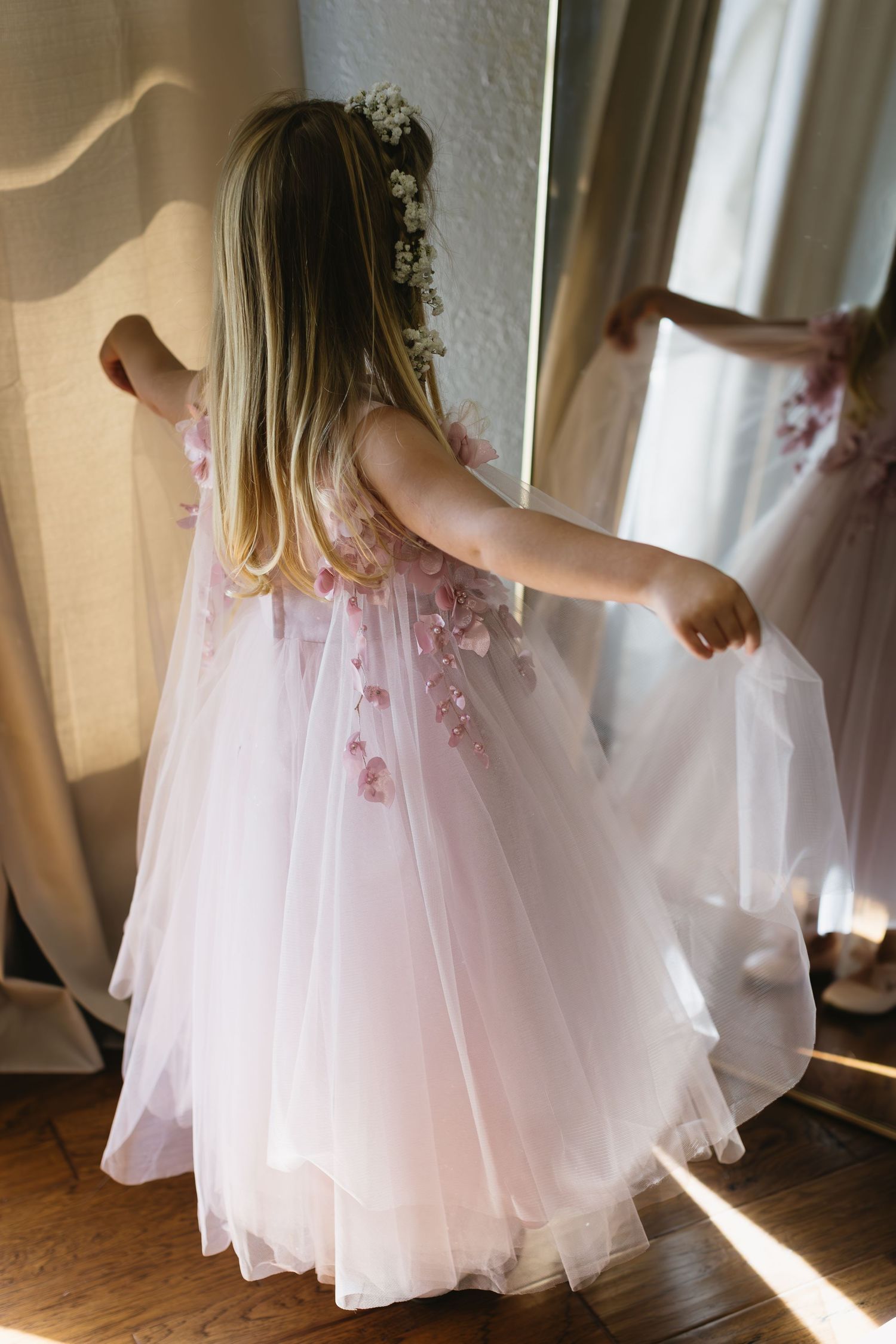 Pink tulle dresses swaying in natural light by a window.