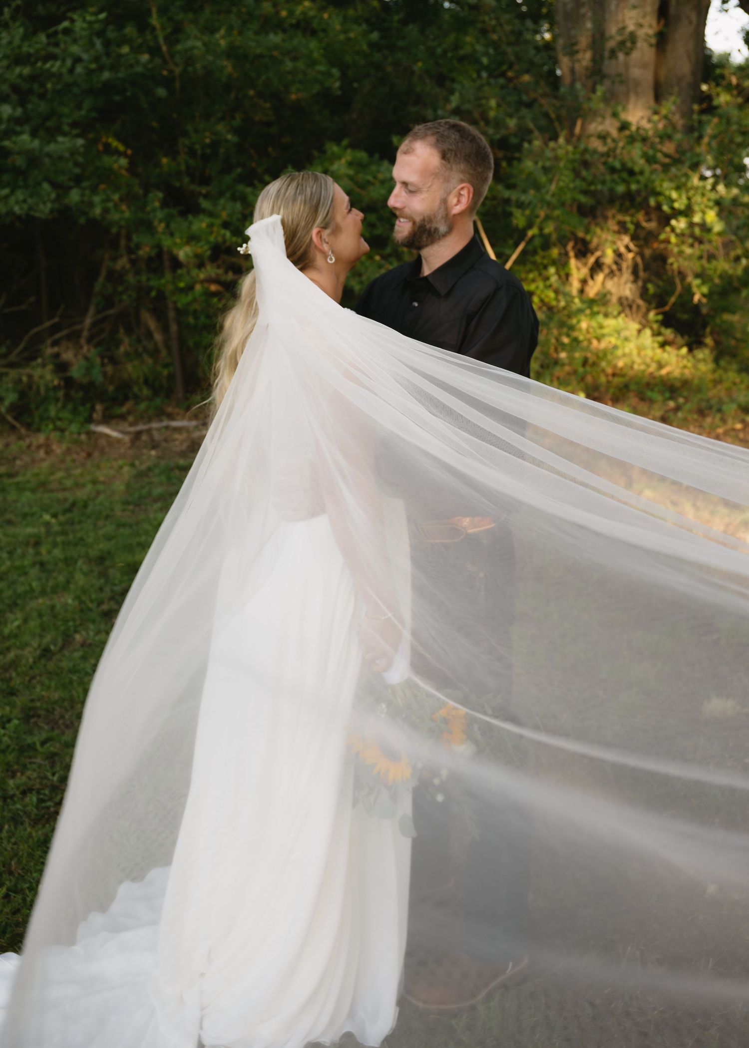 A flowing white wedding veil catches the sunlight during an outdoor portrait session.