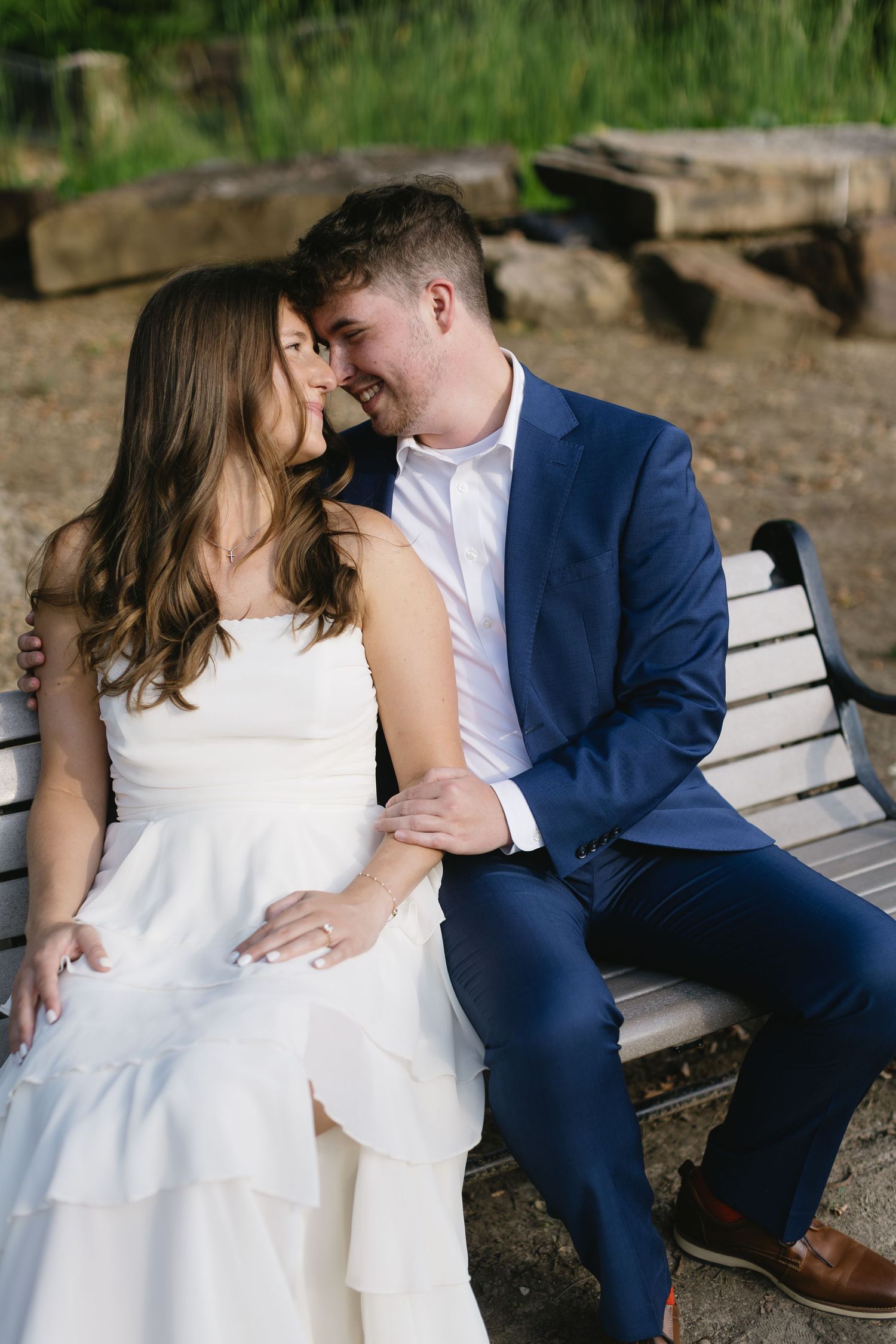 A tender moment shared between a couple sitting on a park bench in formal attire.