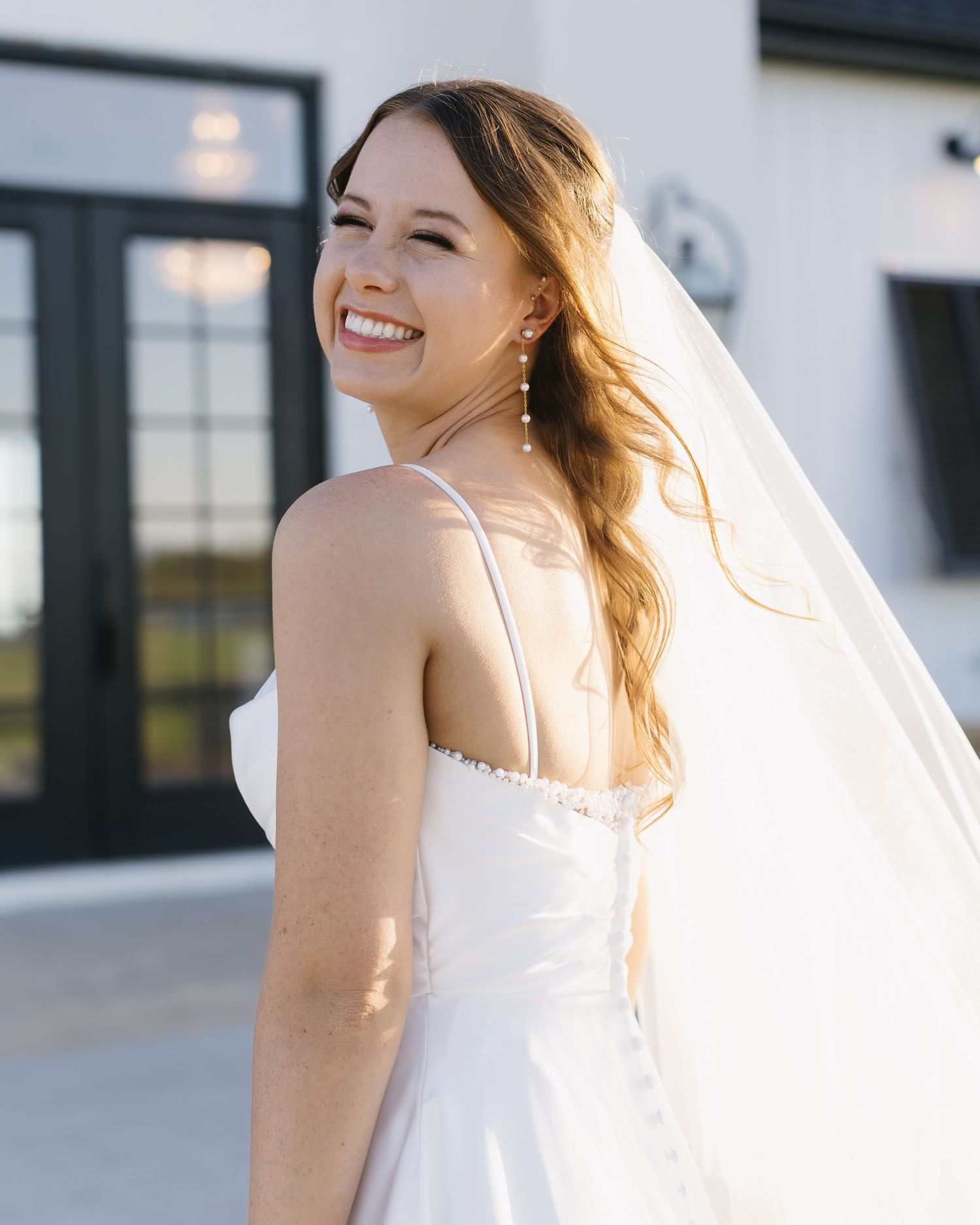 Sun-lit bridal portraits showing movement and joy against a white architectural backdrop.