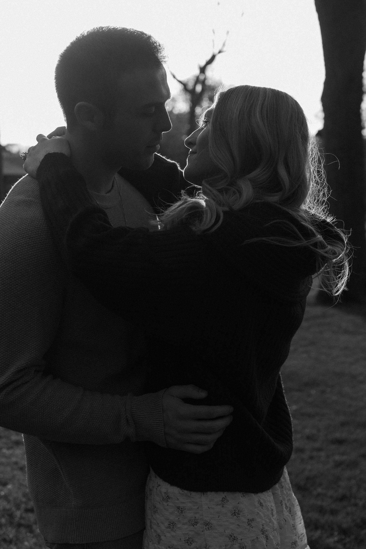 A silhouetted couple embraces during a romantic sunset photoshoot.