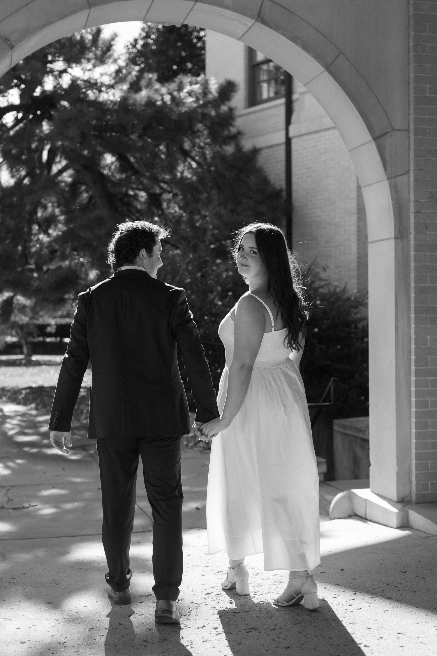Black and white photos under an archway show a couple in formal wear from behind in silhouette.