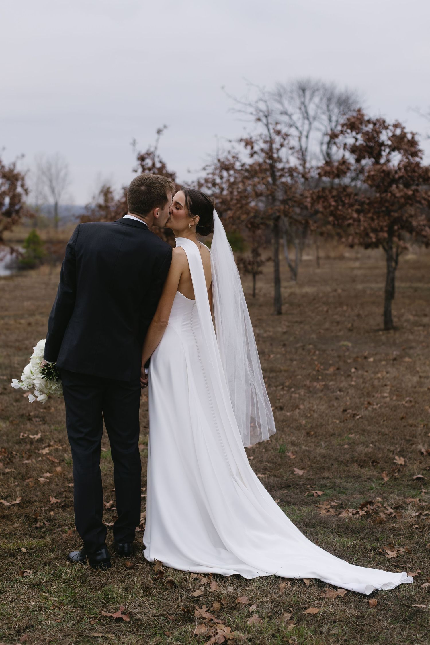Elegant white wedding dress with flowing train captured in outdoor setting.