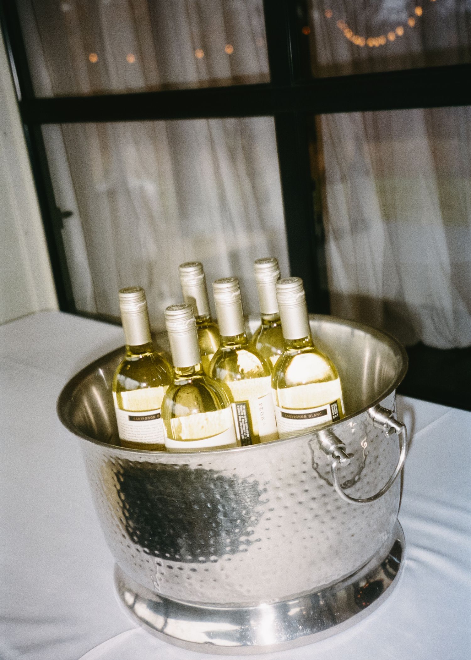 Wine bottles chilling in a hammered silver ice bucket at an event.