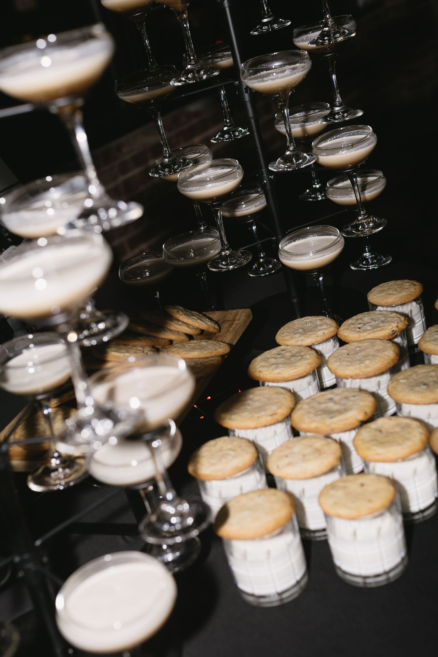 Rows of desserts and champagne glasses arranged on a dark table at an elegant event.