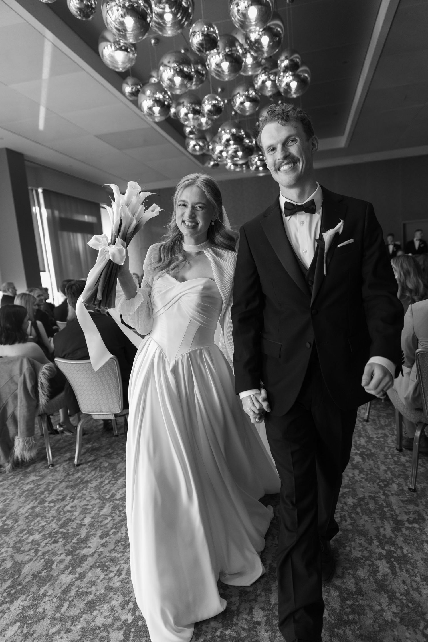 Wedding celebration under crystal chandeliers with joyful dancing and laughter.