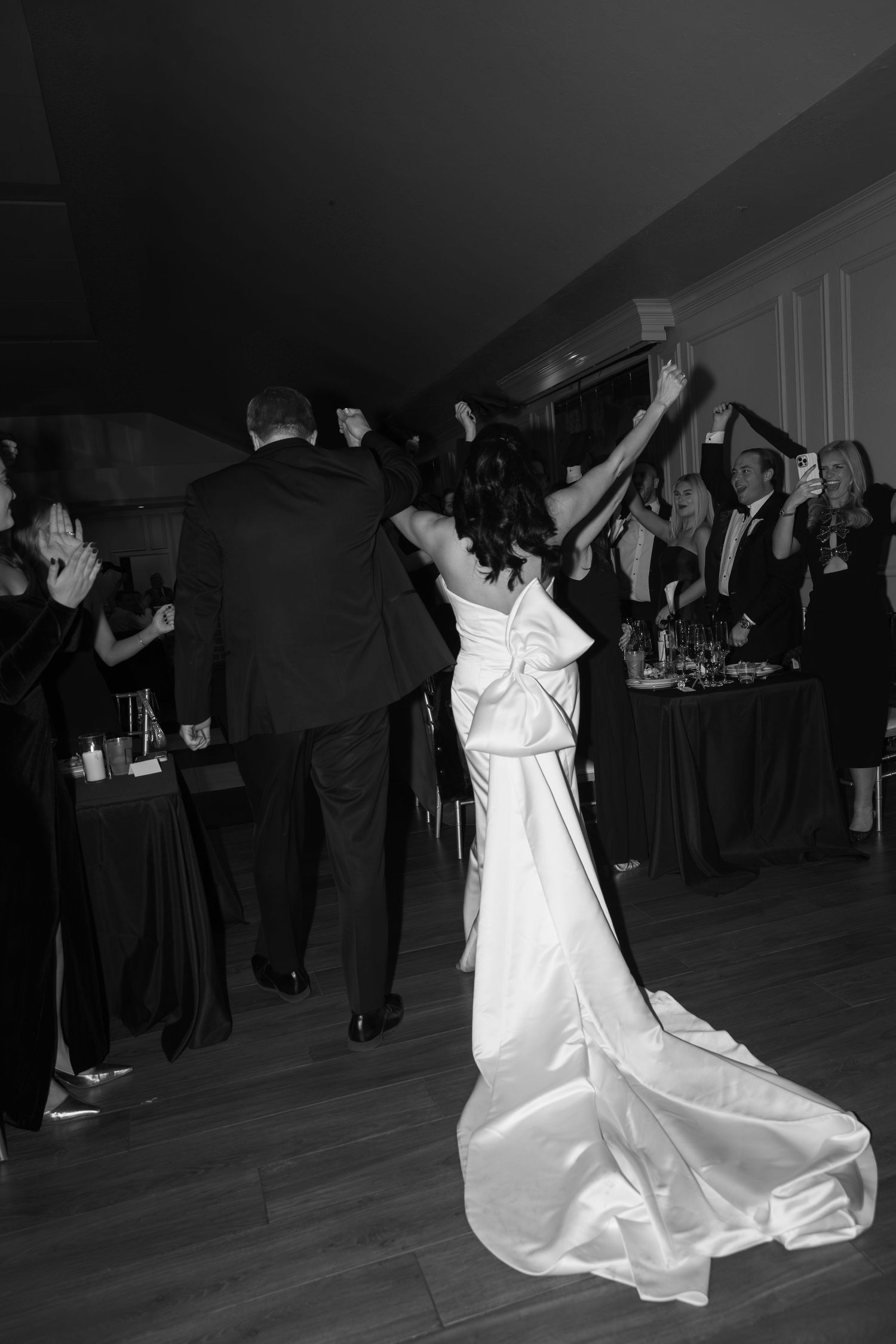 A couple dancing at a wedding reception with the bride in a flowing white gown surrounded by guests.