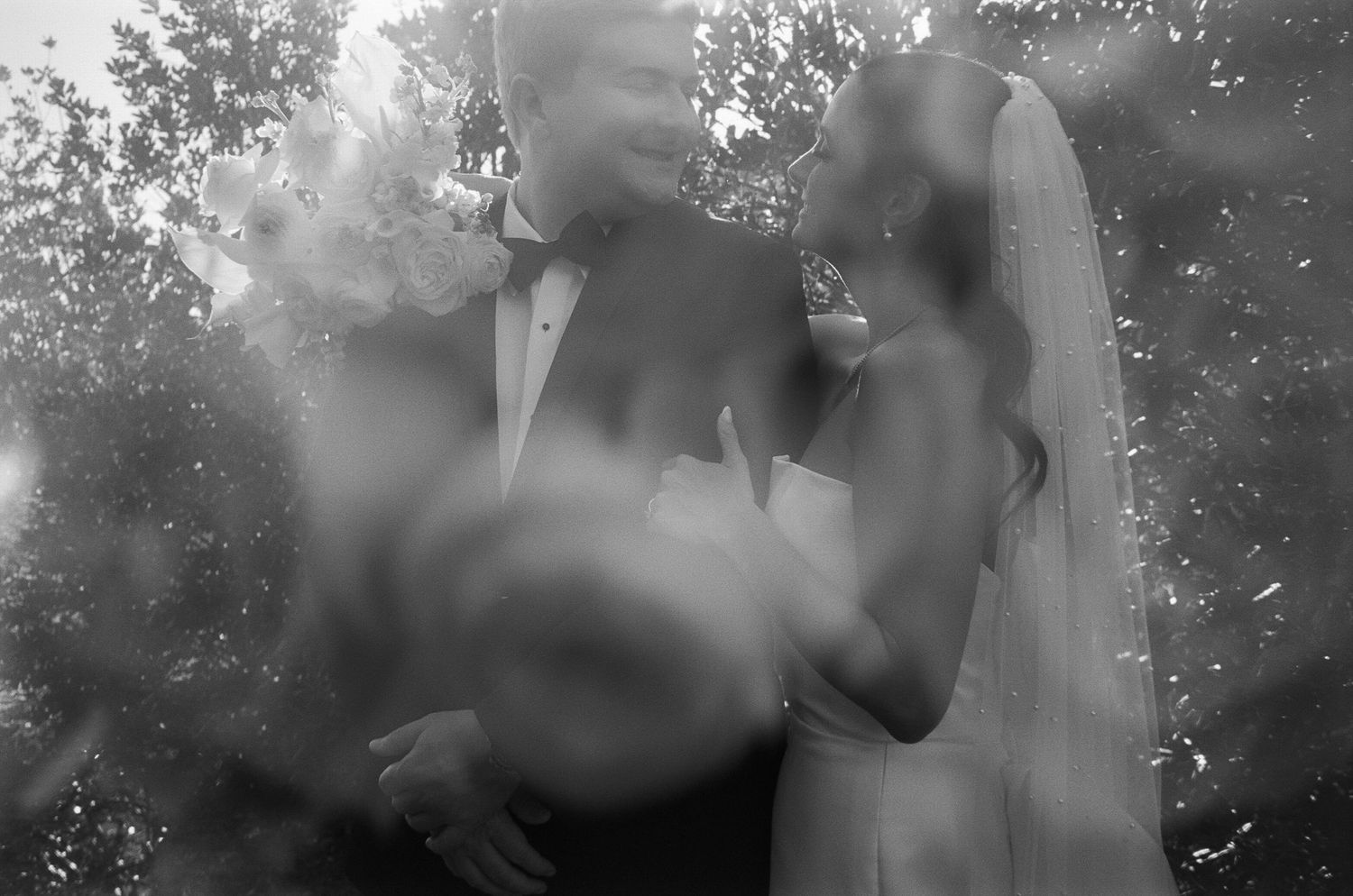 Black and white artistic wedding portrait with soft focus and natural lighting.