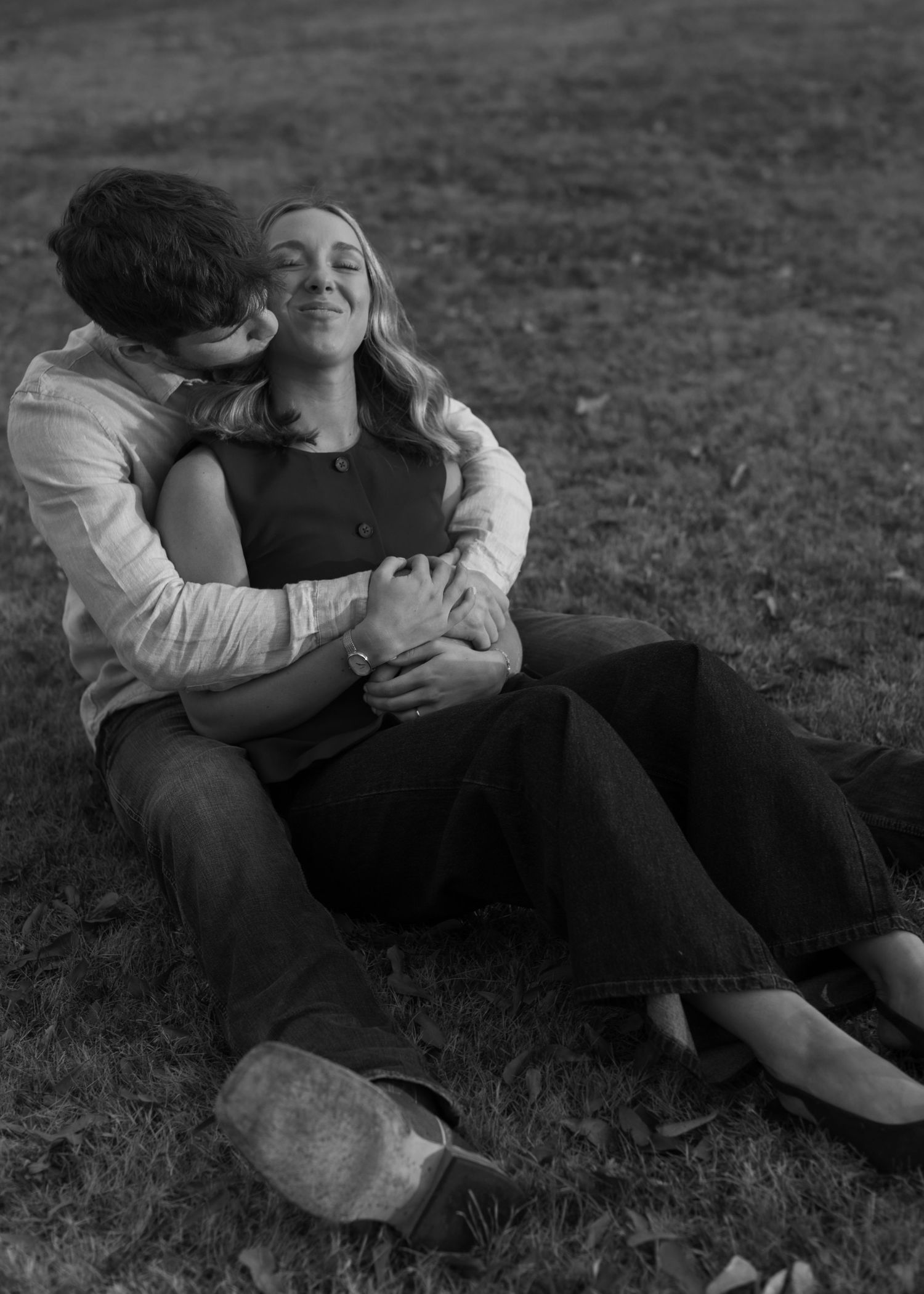 Couple relaxing together on grass in casual romantic pose.