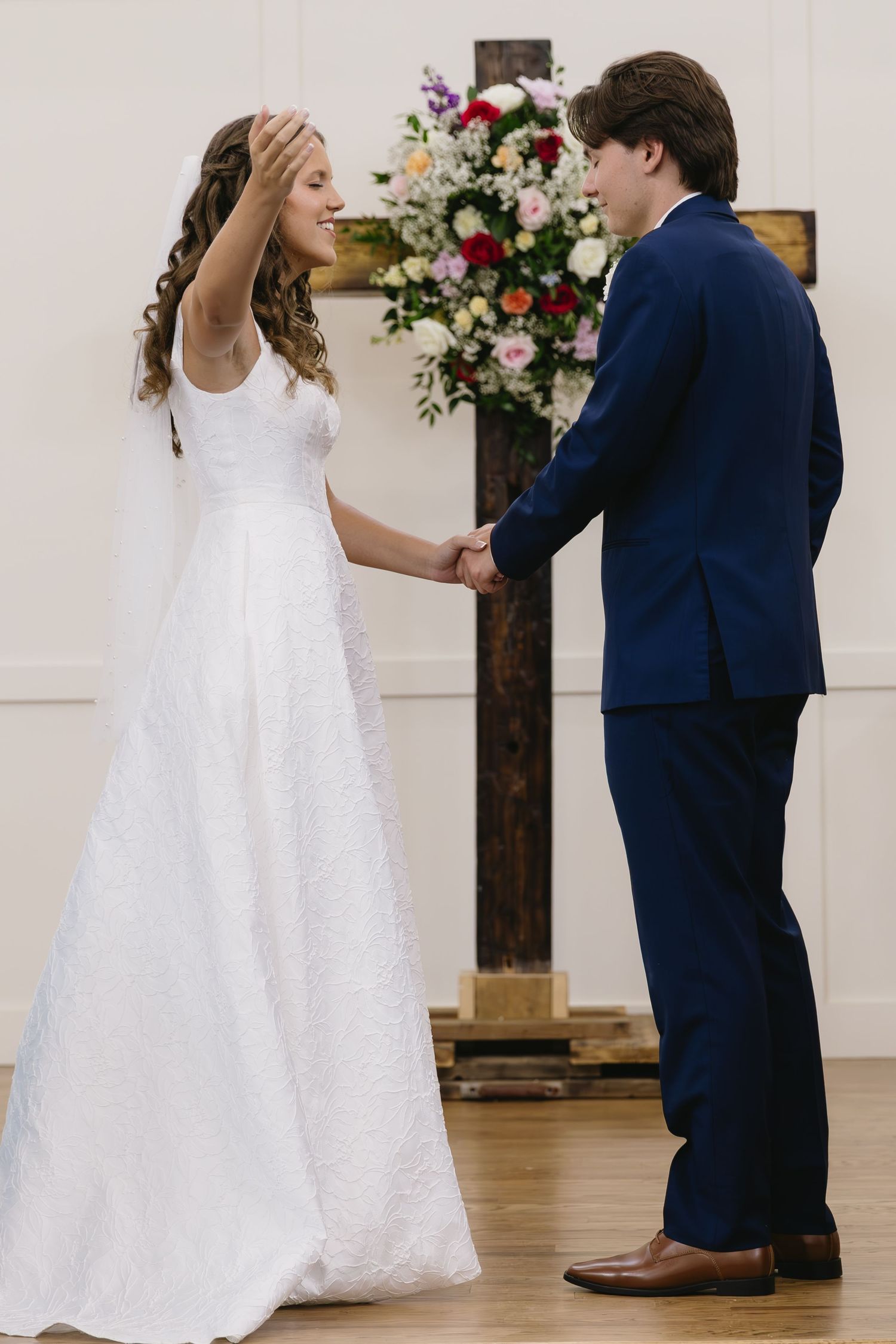 Couple performs romantic dance moves in a church with floral arrangements and white decor.