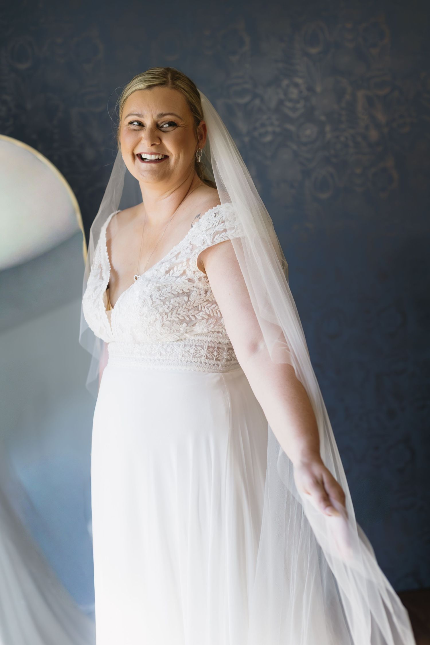 Flowing white wedding dress with lace bodice against dark blue backdrop.