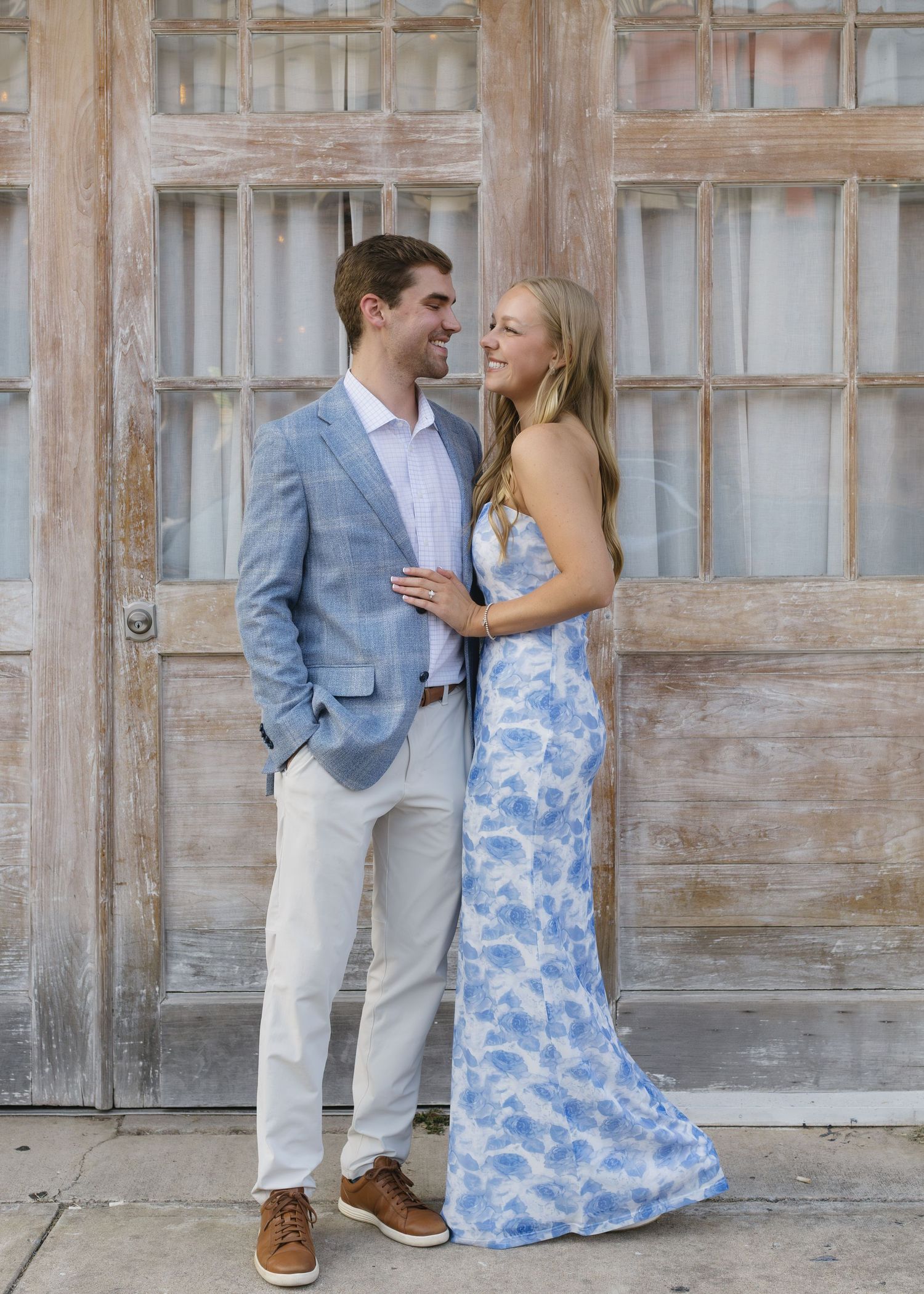 A couple shares playful moments against a rustic wooden wall backdrop.