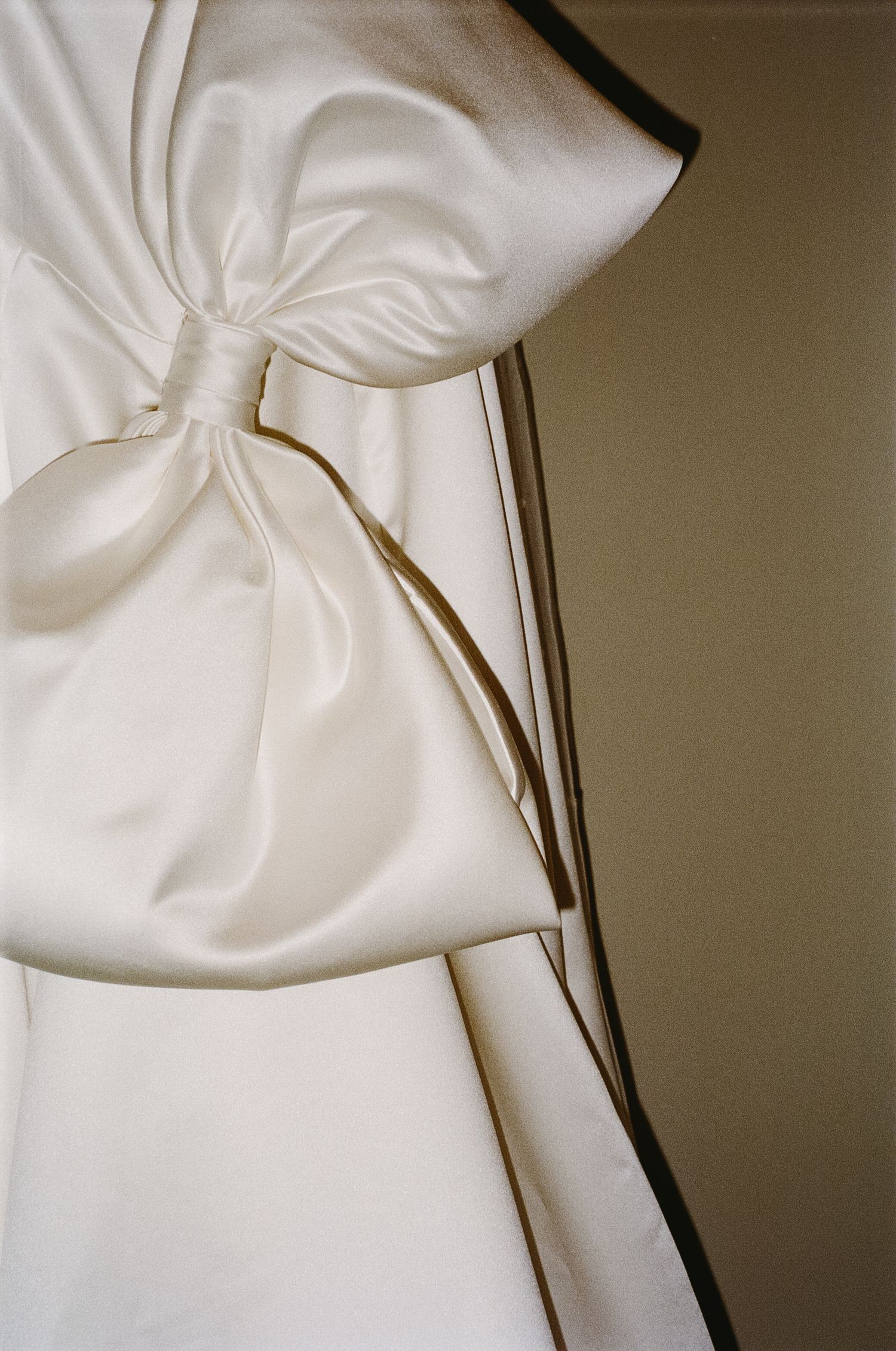 Close-up detail of white satin fabric with elegant pleating and folds.