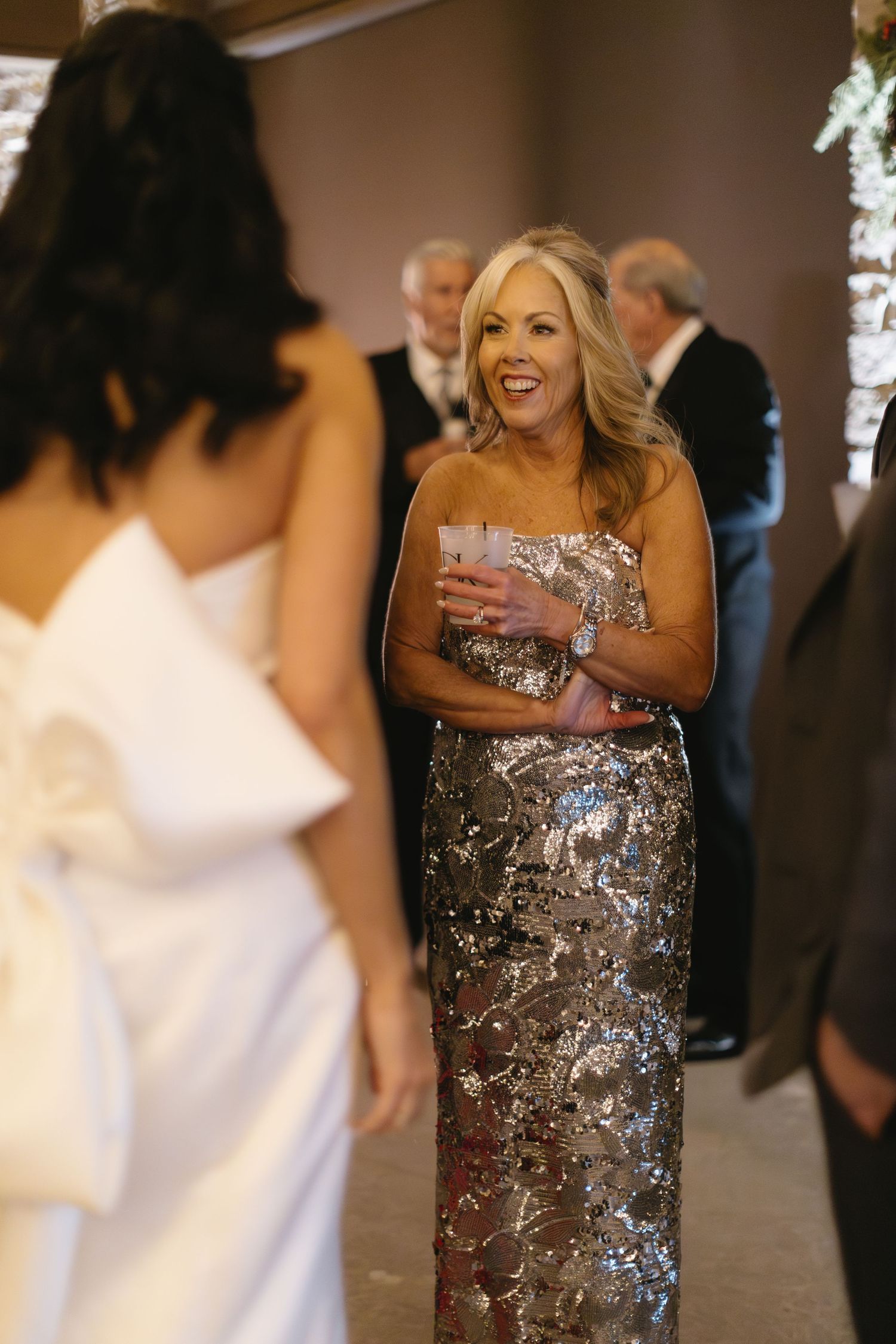Guest in metallic dress sharing joyful moment at wedding reception.