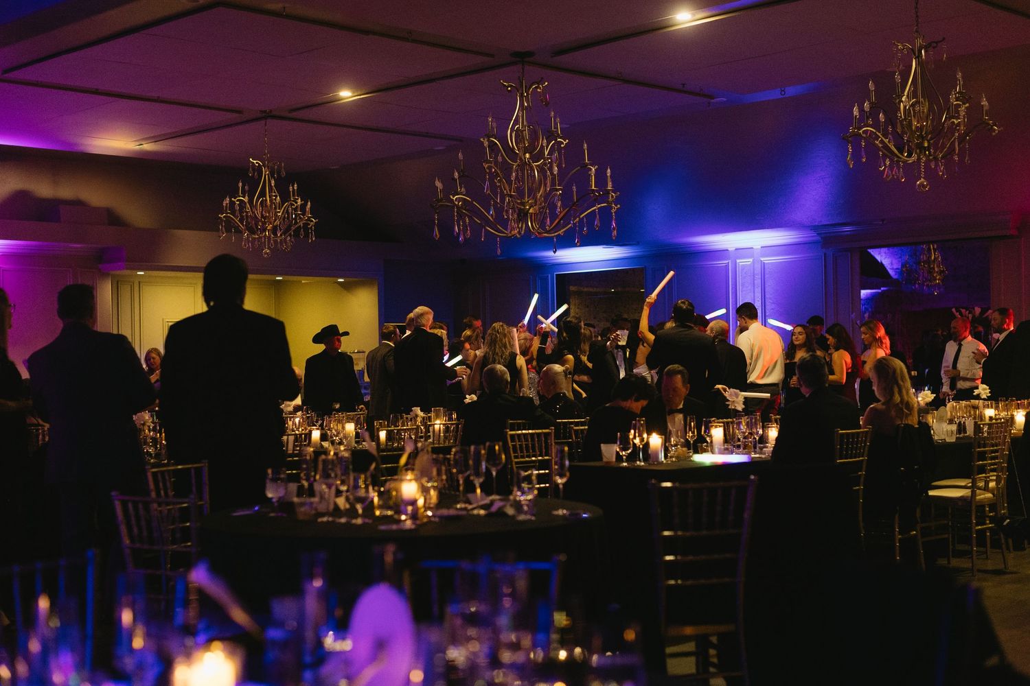 Dark reception hall illuminated with blue and purple lighting and chandeliers.
