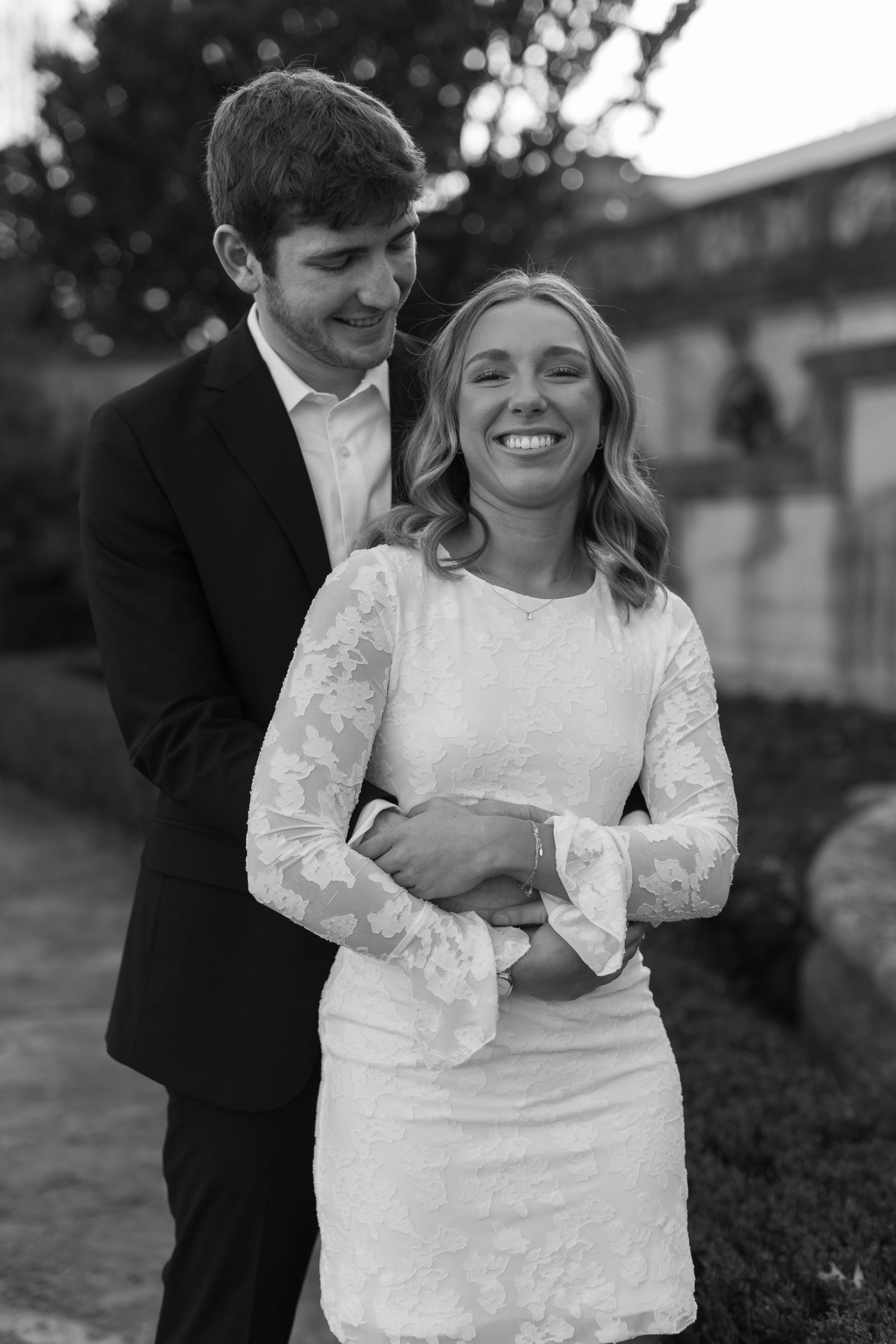 A romantic moment captured between a couple in formal attire standing outdoors at dusk.