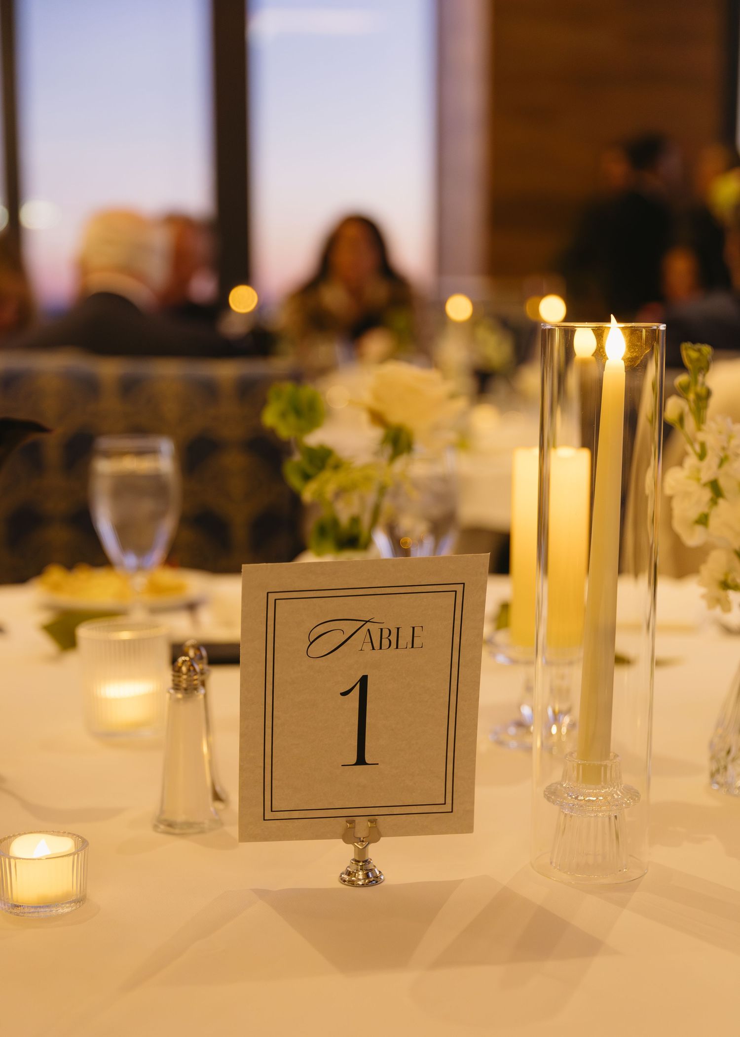 Wedding reception table setting with candles and table number card.