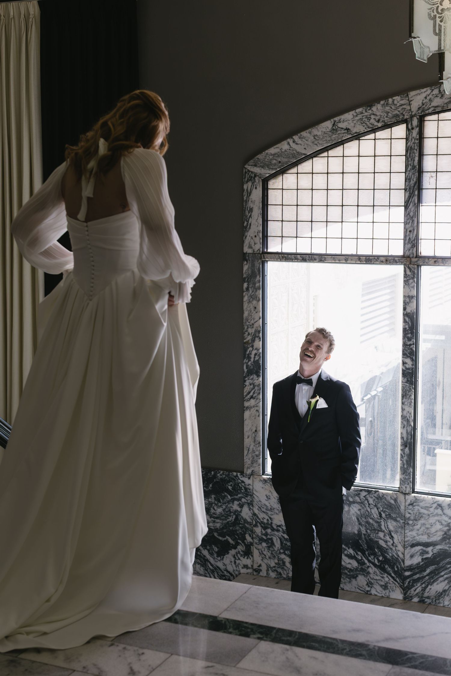 Wedding photoshoot in industrial space with large windows and dramatic lighting.