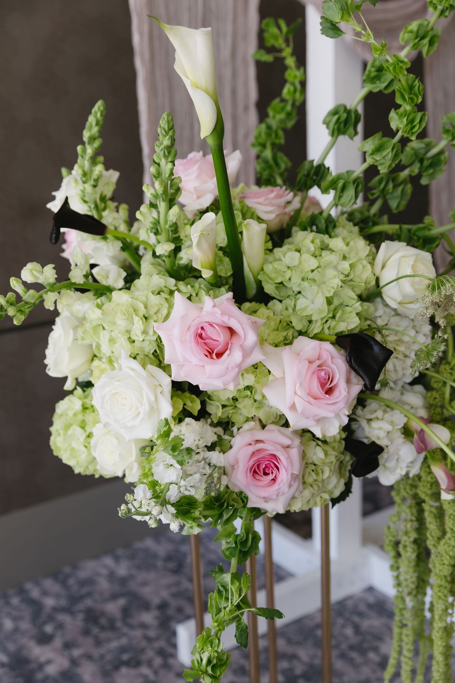 Elegant floral arrangement with pink roses and white hydrangeas on tall stands for wedding decor.