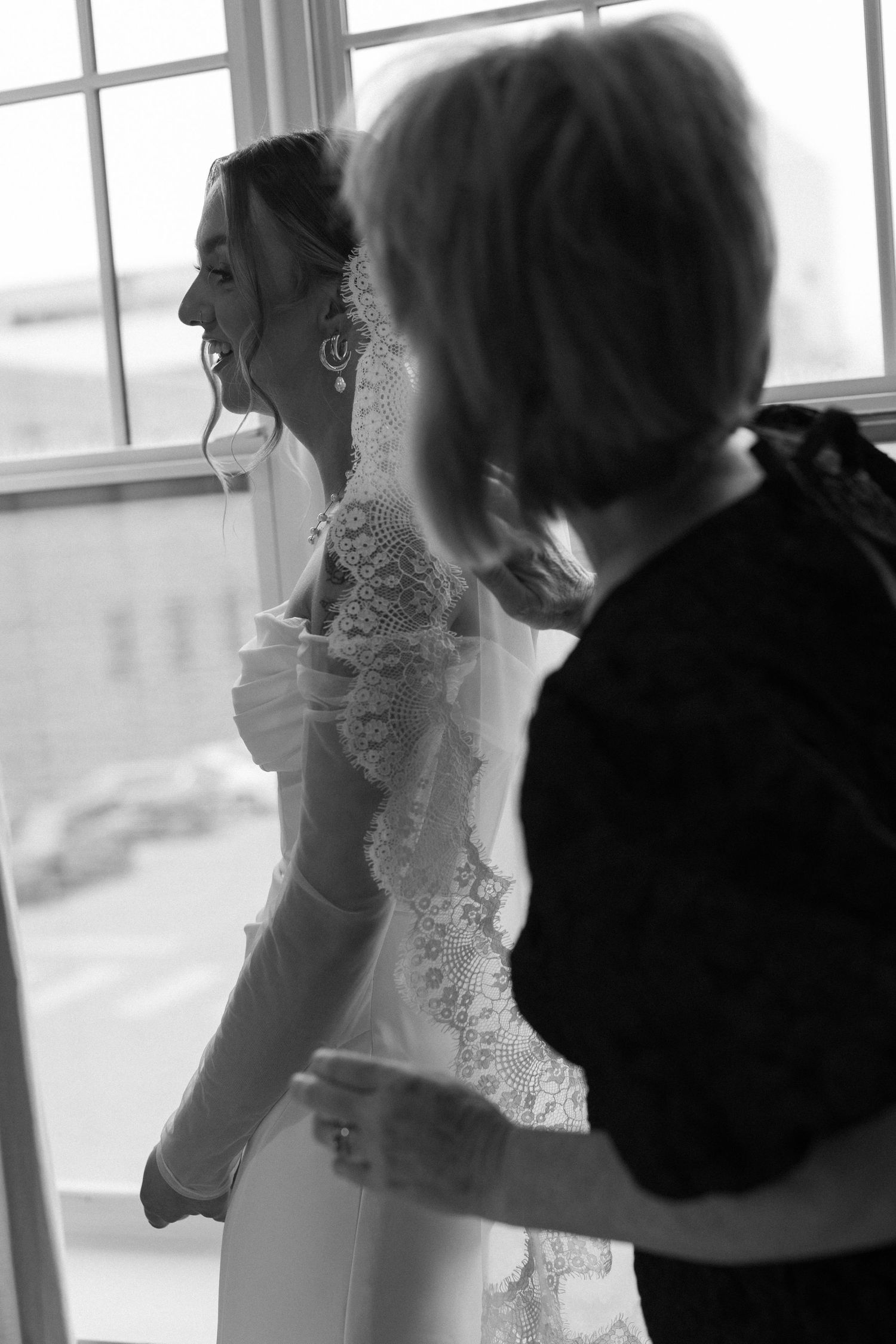 People in formal attire gathered near a bright window.