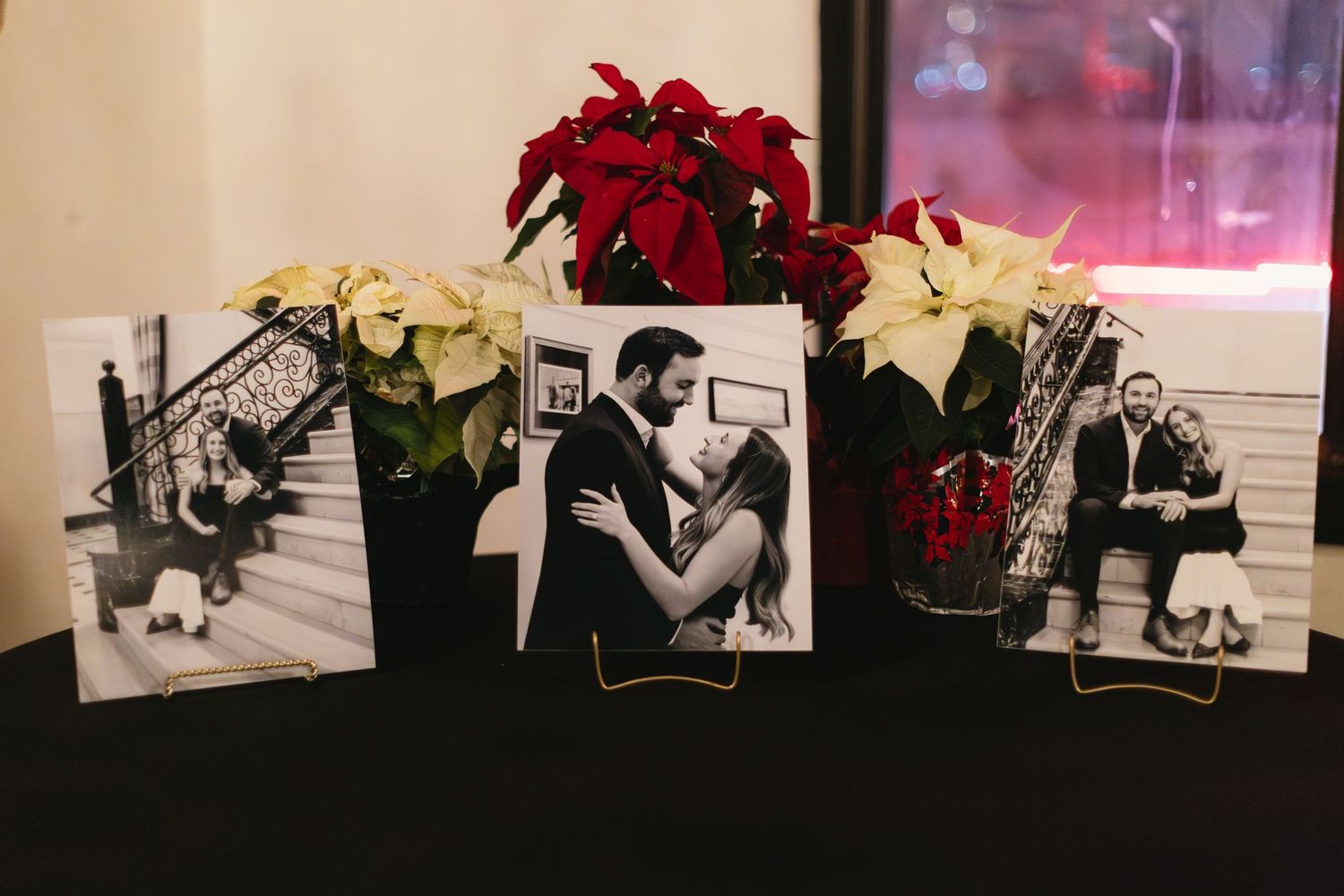 Black and white photographs displayed with red and white poinsettia flowers in a holiday decor arrangement.