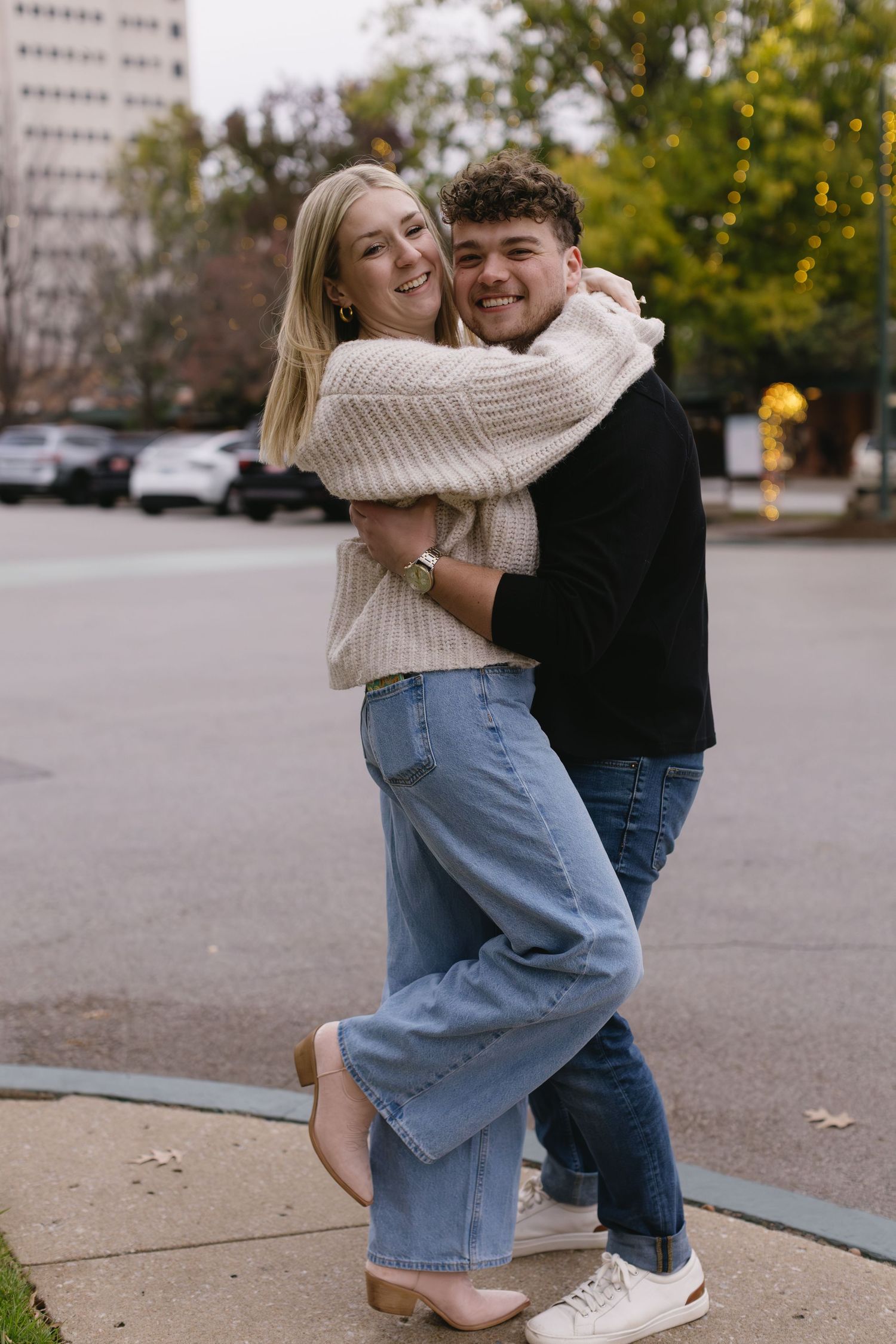 A couple dances and embraces on an autumn sidewalk.