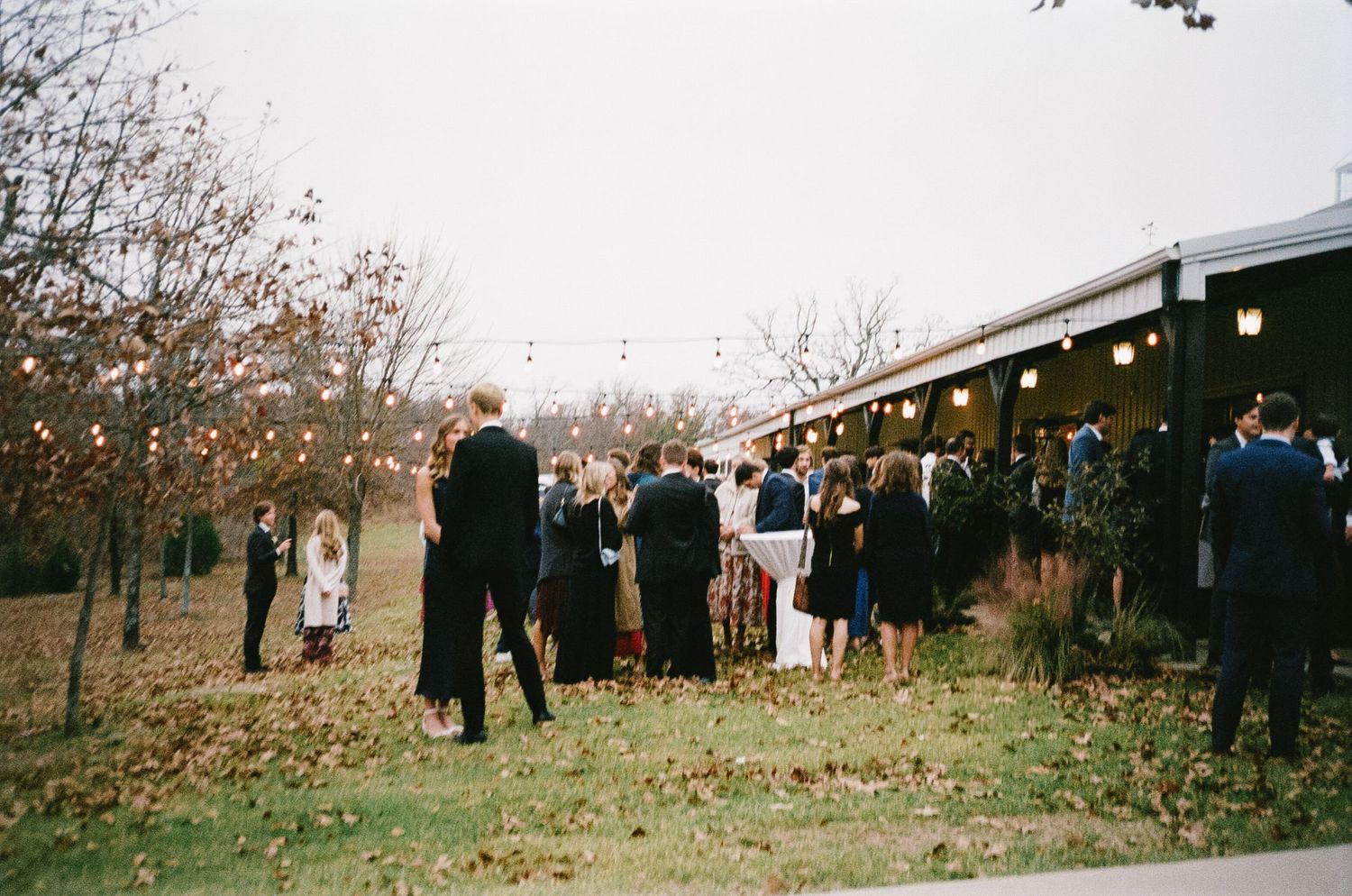 Outdoor wedding venue with guests gathering on an autumn day.