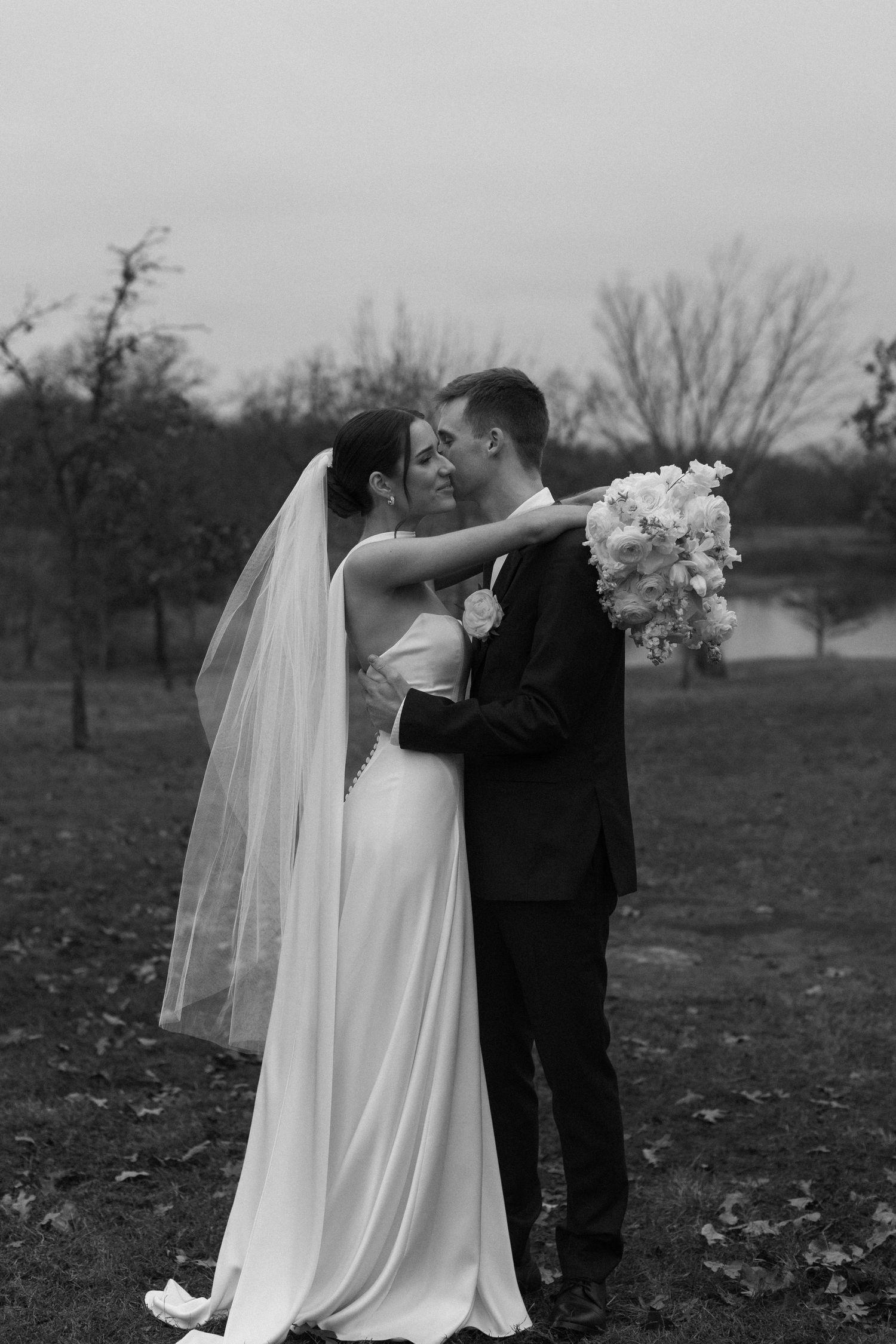 Black and white wedding portraits captured in a rustic outdoor setting with fall foliage.