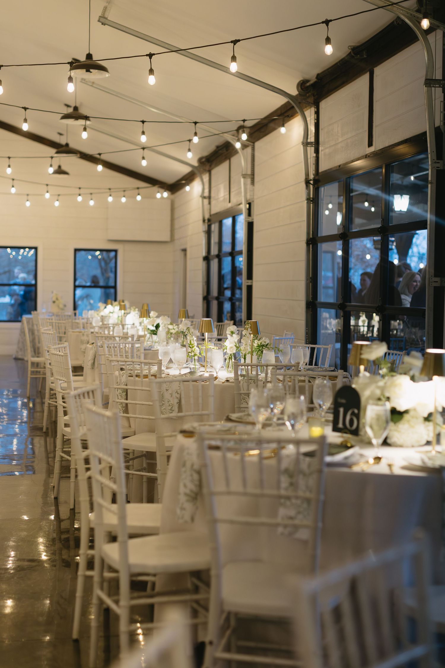 Elegant wedding reception venue with white chairs and string lights creating a romantic atmosphere.
