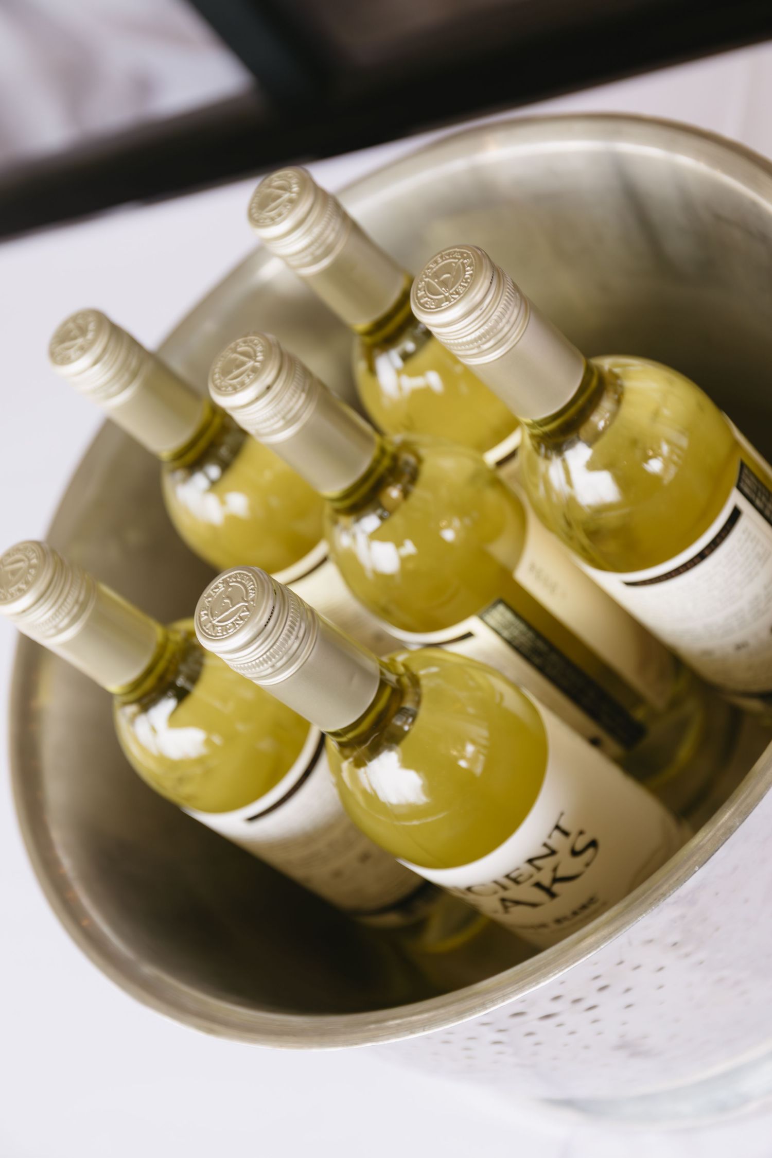 Chilled white wine bottles arranged in an elegant ceramic bowl.