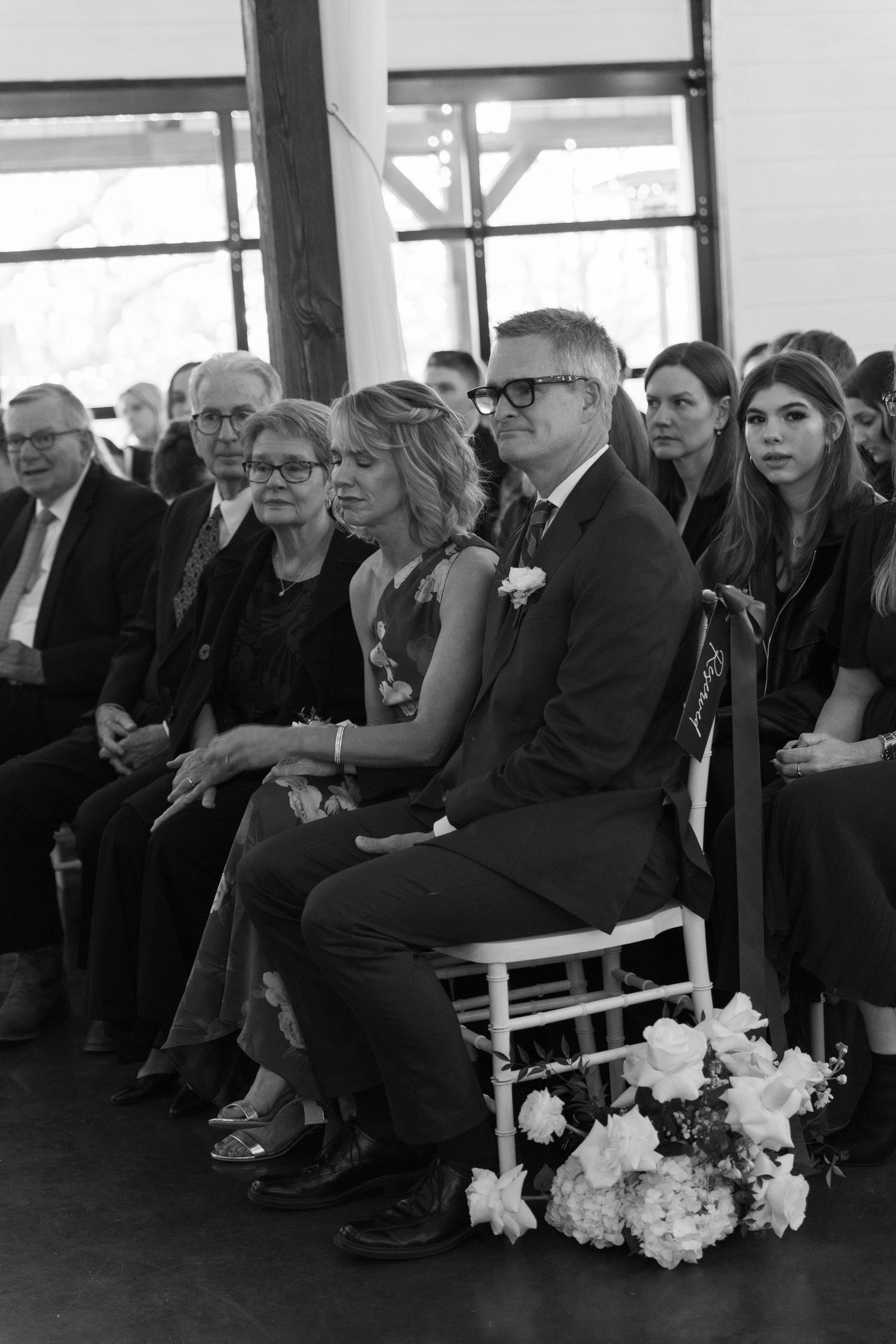 Wedding ceremony guests seated in rows with white floral decorations.