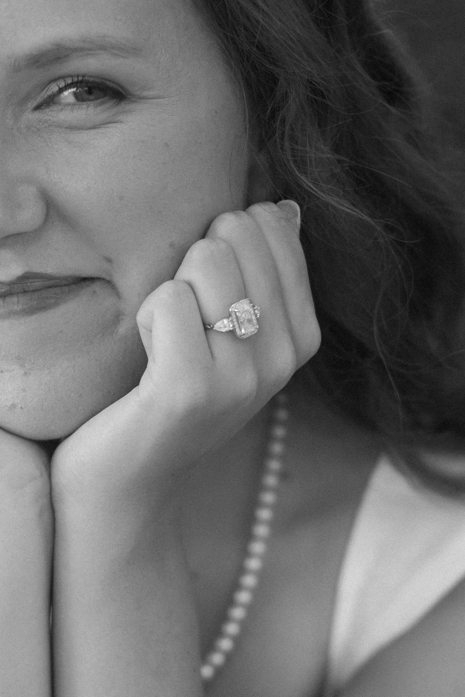 Black and white series showing close-up shots of someone smiling while displaying an engagement ring.