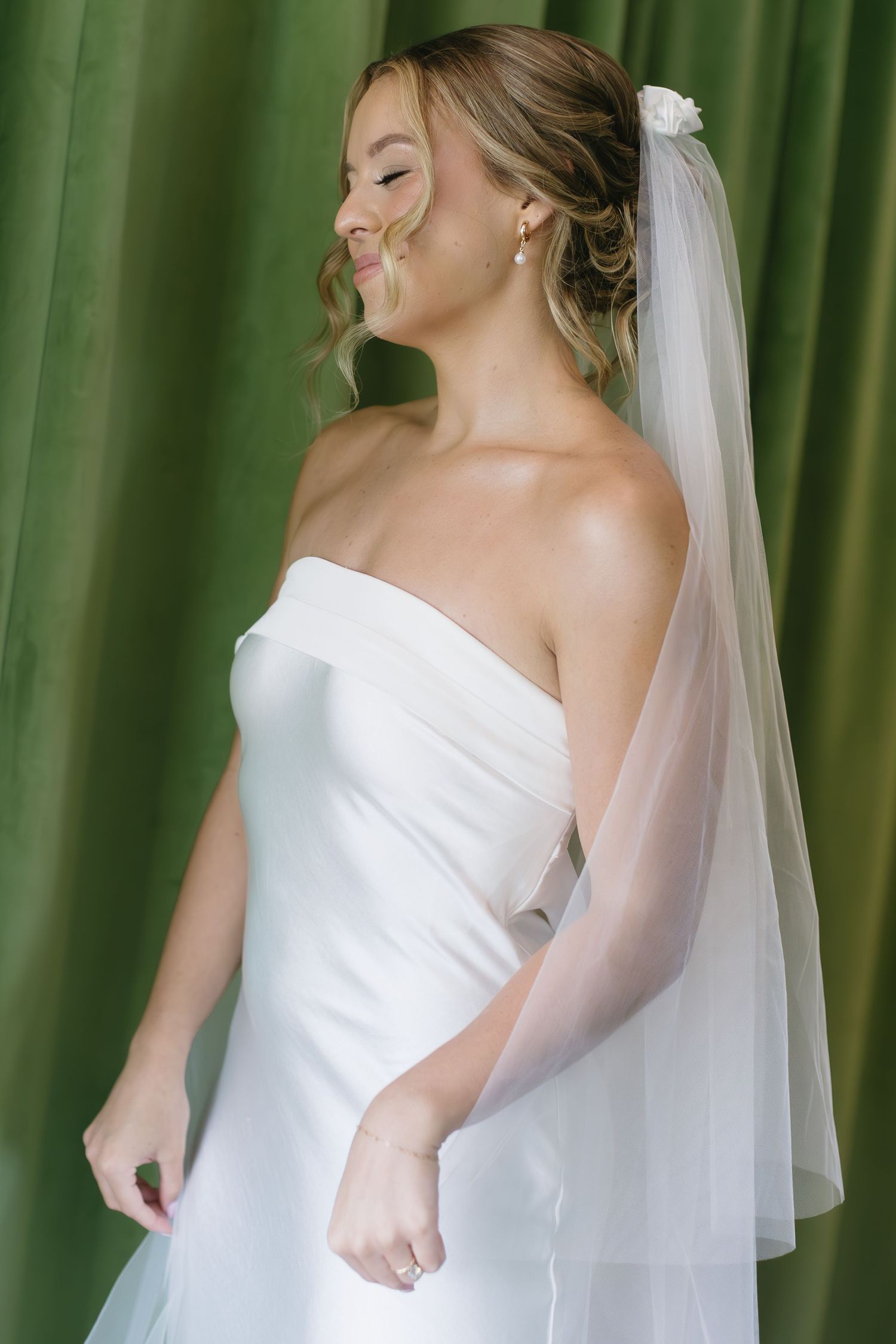Elegant bridal portraits showing a strapless white gown against a green curtain backdrop.